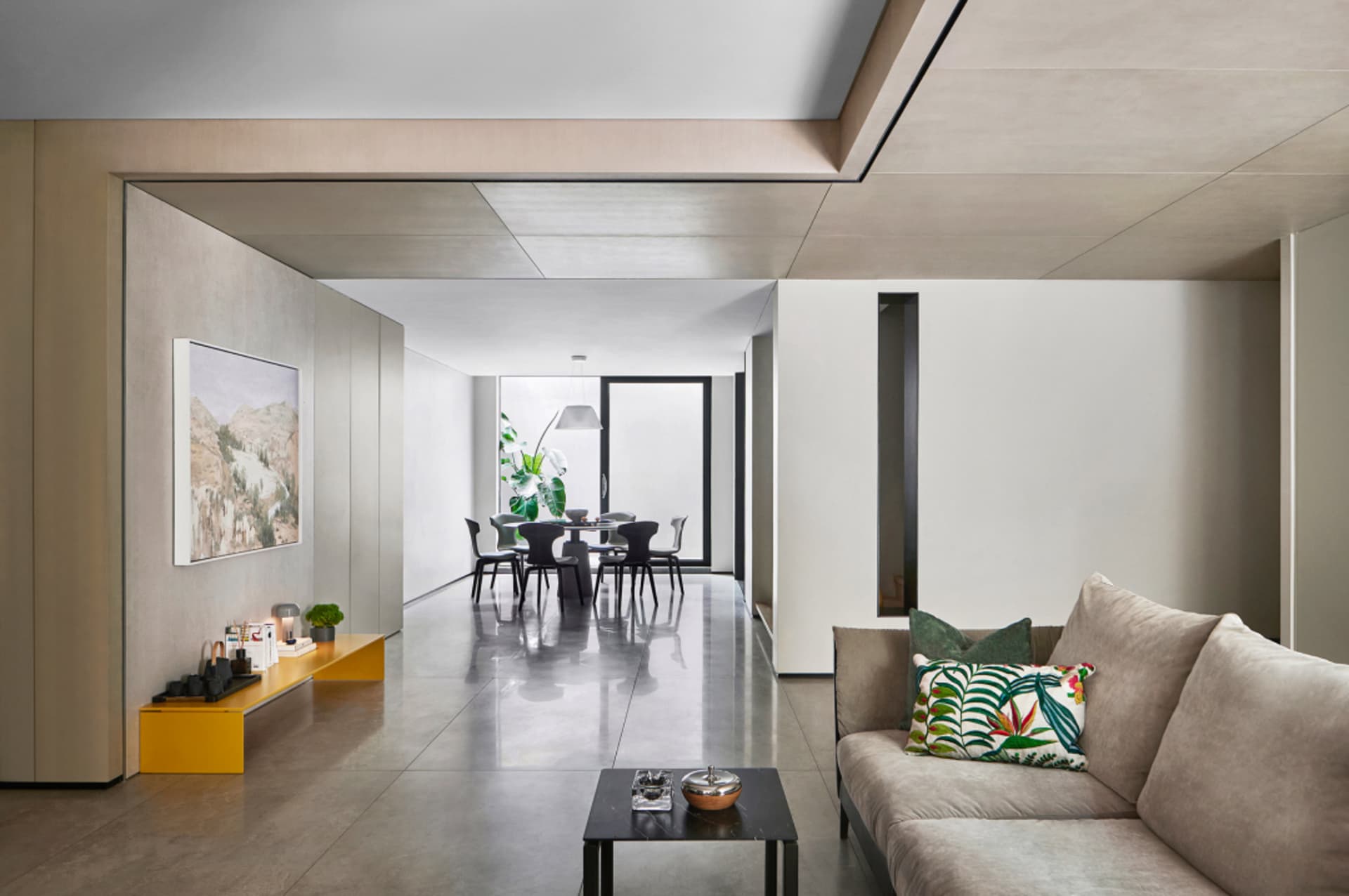 A modern living room with concrete walls and a glass partition.
