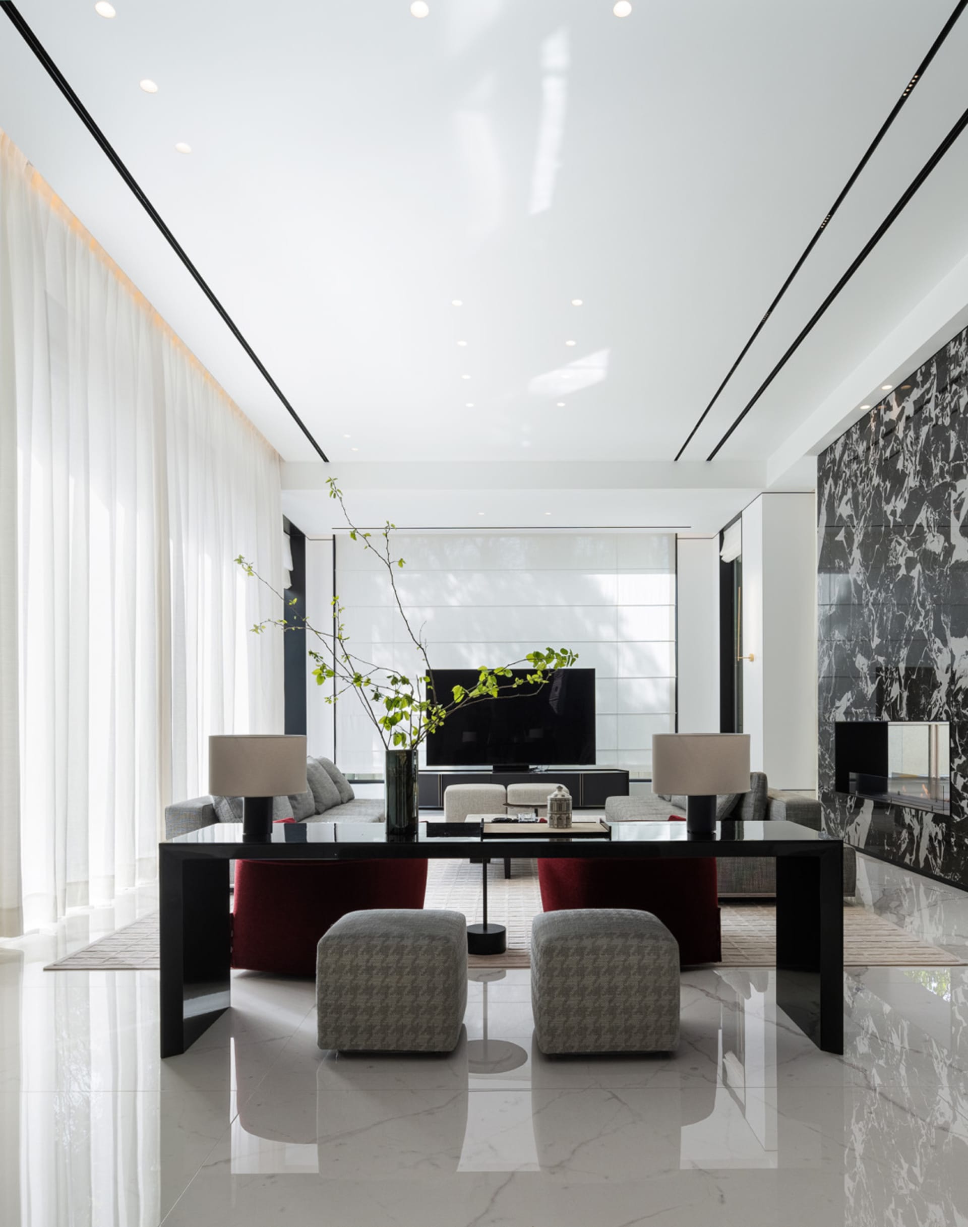 Modern living room featuring marble and glass materials with contemporary furniture and a large television.