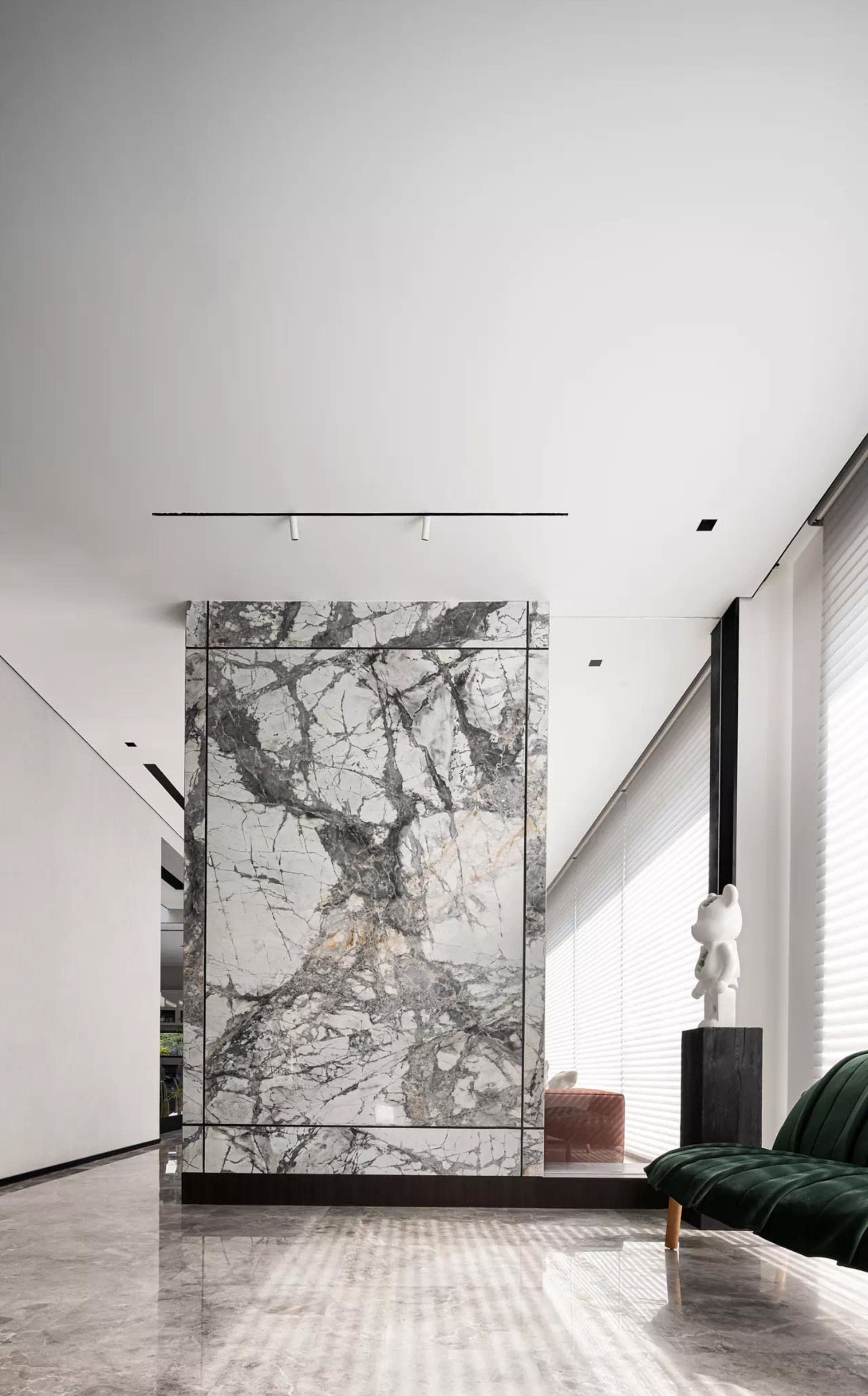 Modern living room featuring marble walls and floor, minimalist decor, and large windows.
