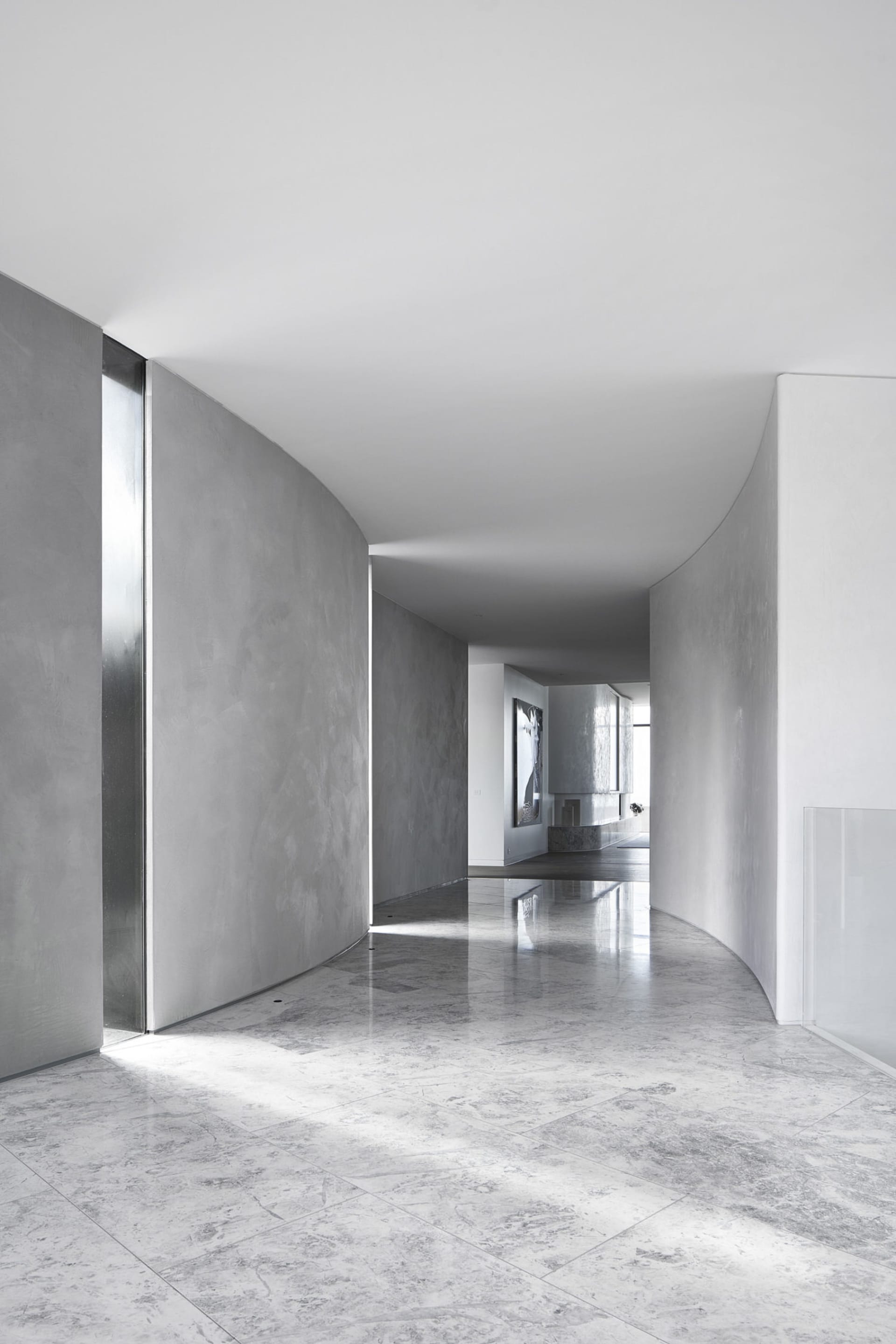 Modern minimalist living room with marble flooring and walls, featuring sleek, clean lines and a serene atmosphere.