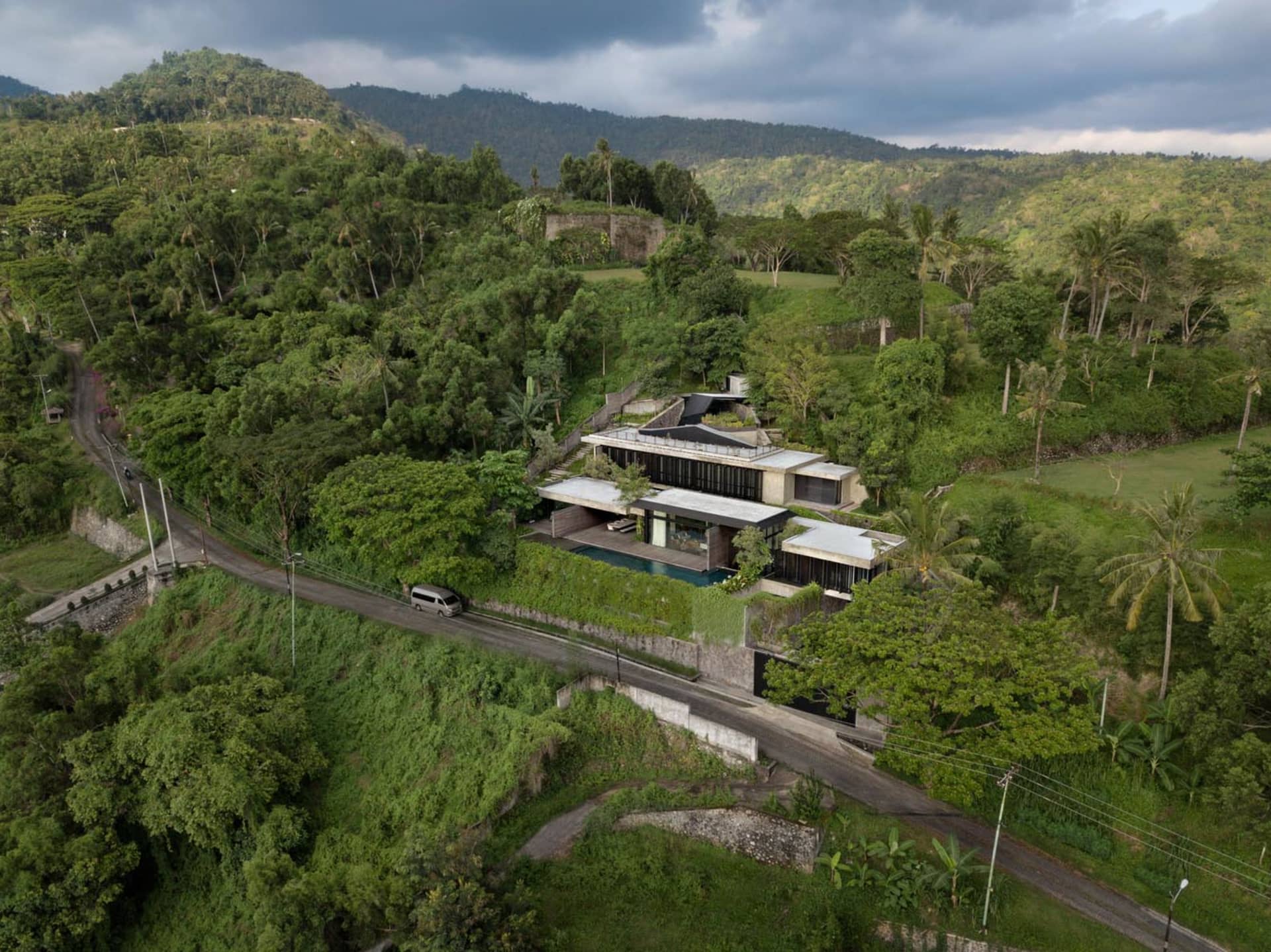 一座現代住宅房屋，外牆採用混凝土材質，位於山坡上並設有泳池。