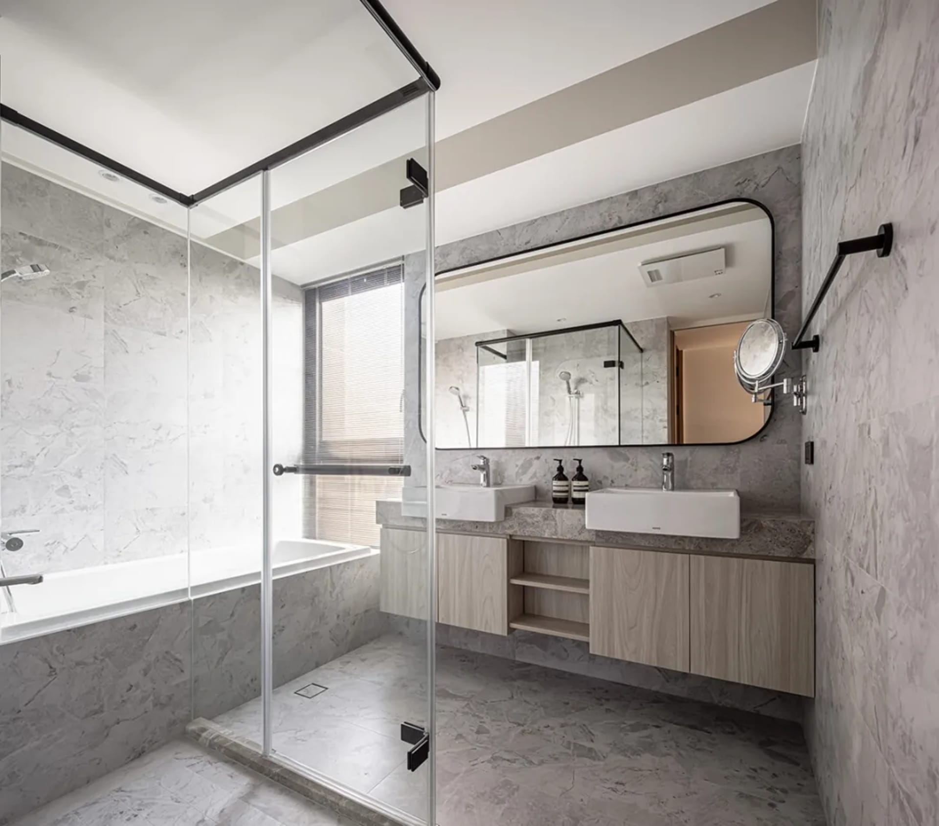 Modern minimalist bathroom featuring marble walls and floor, glass shower enclosure, and double sink vanity.
