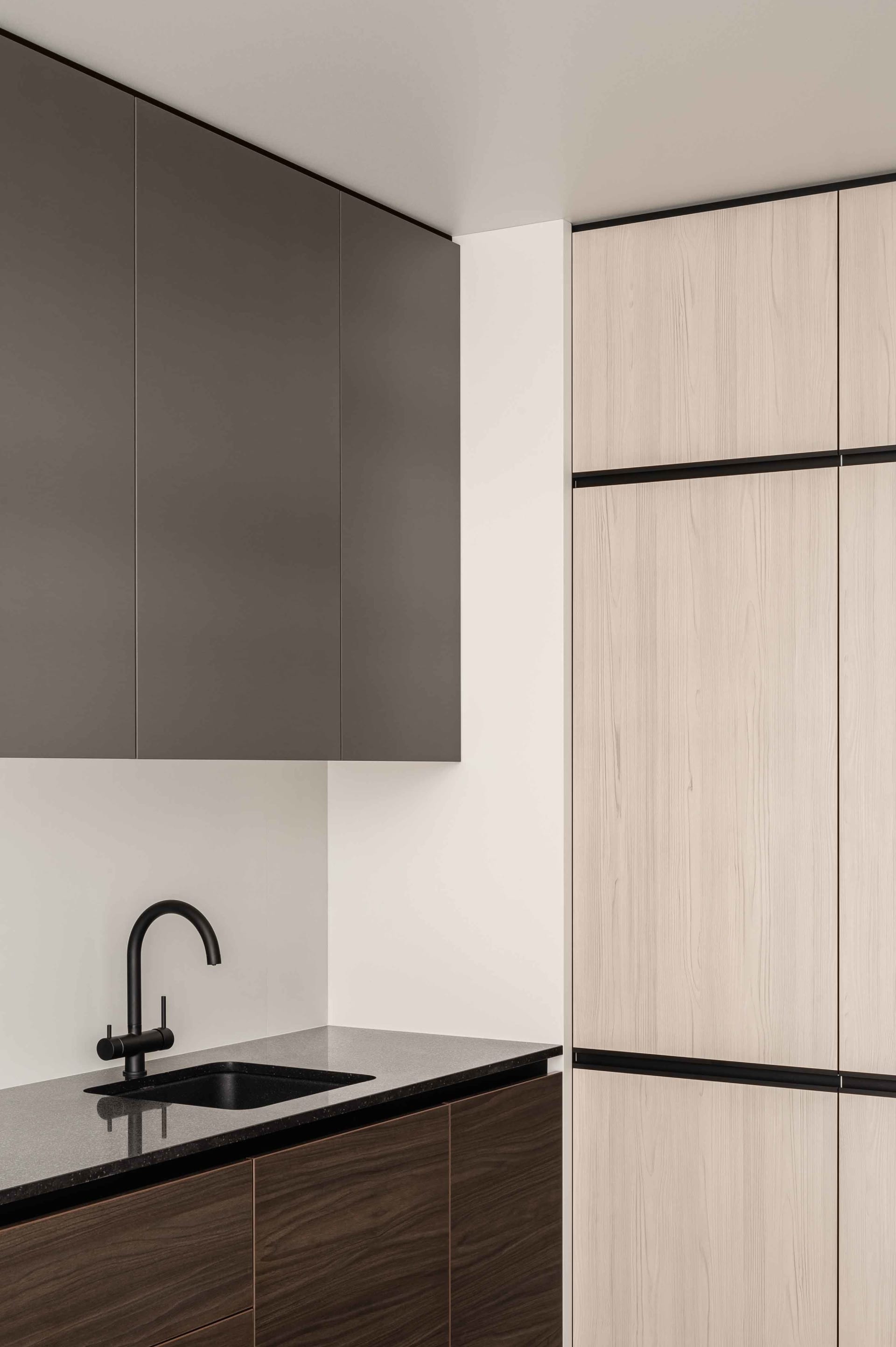 A modern kitchen featuring black countertops and wooden cabinets.