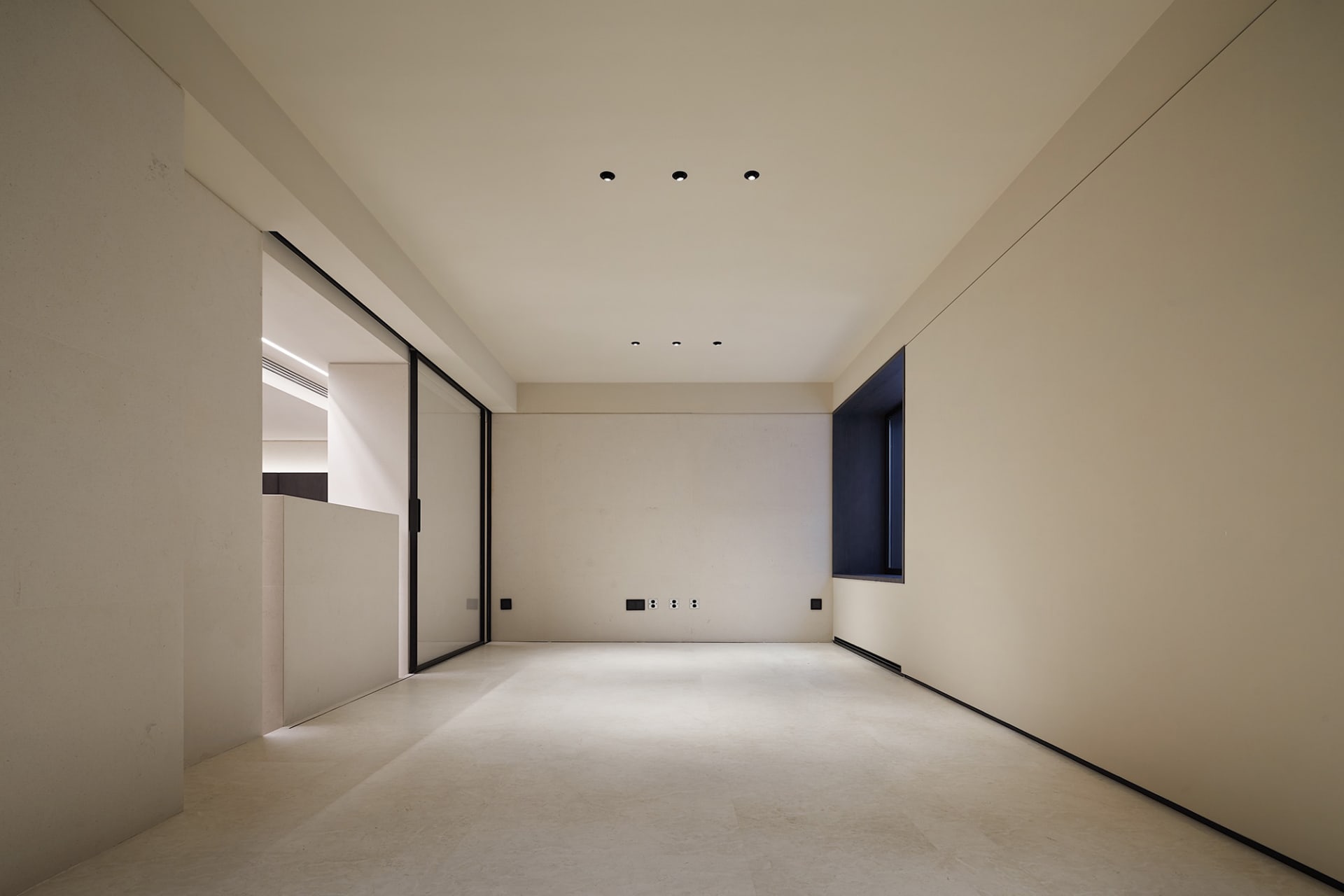 An empty minimalist interior space featuring concrete walls and floor.