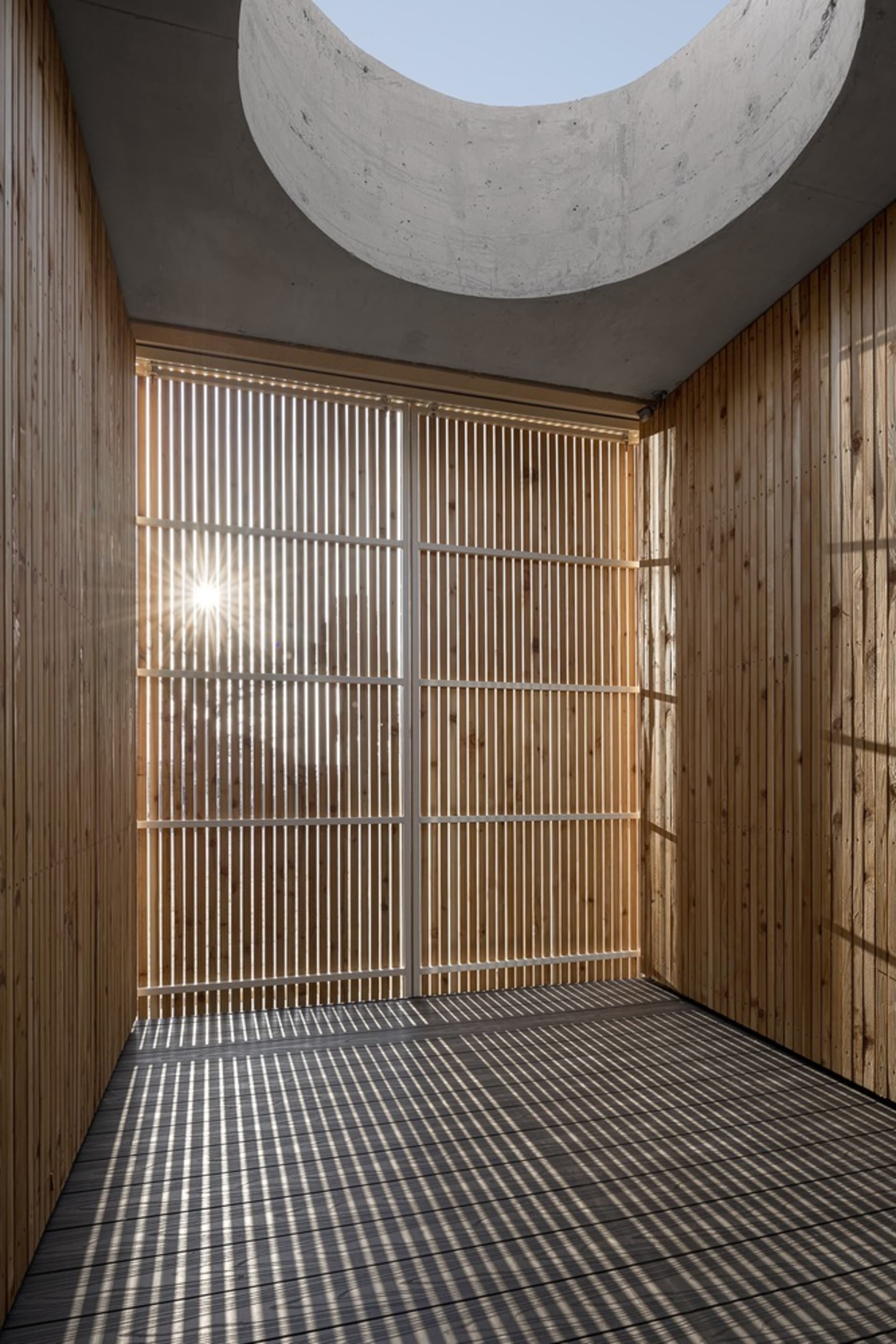 Sunlight streaming through wooden lattices in a minimalist interior space