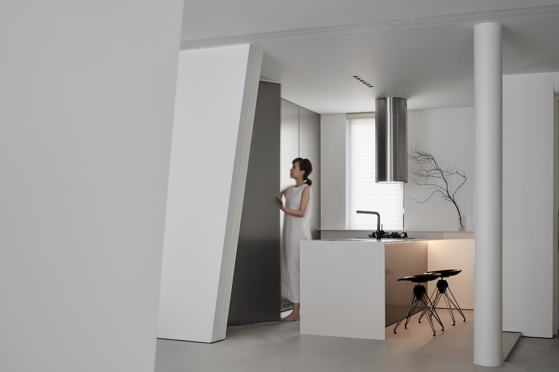 Modern, minimalist kitchen with white concrete surfaces, stainless steel appliances, and a sleek design.