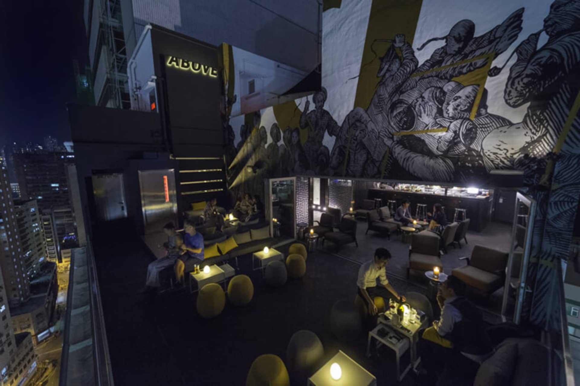A rooftop bar with modern seating and a mural of warriors.