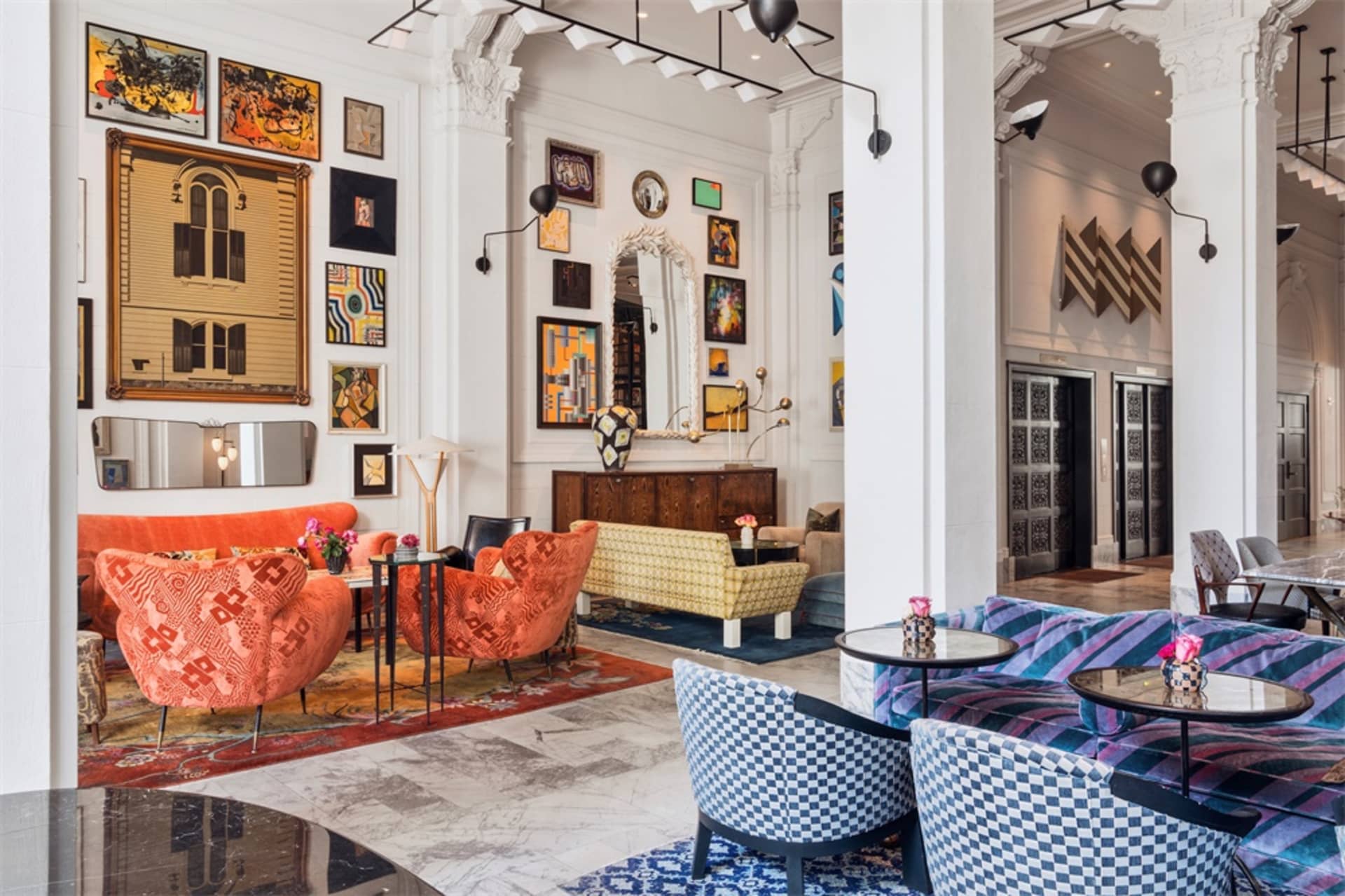 A vibrant, modern hotel lobby featuring concrete walls, patterned furniture, and a variety of art installations.