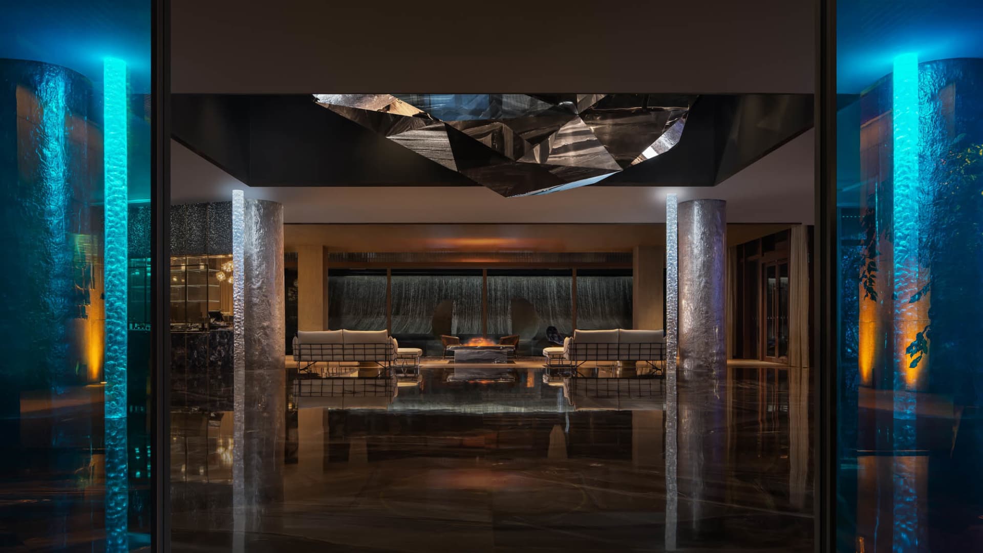 A modern lobby with glass partitions and a geometric ceiling decoration.