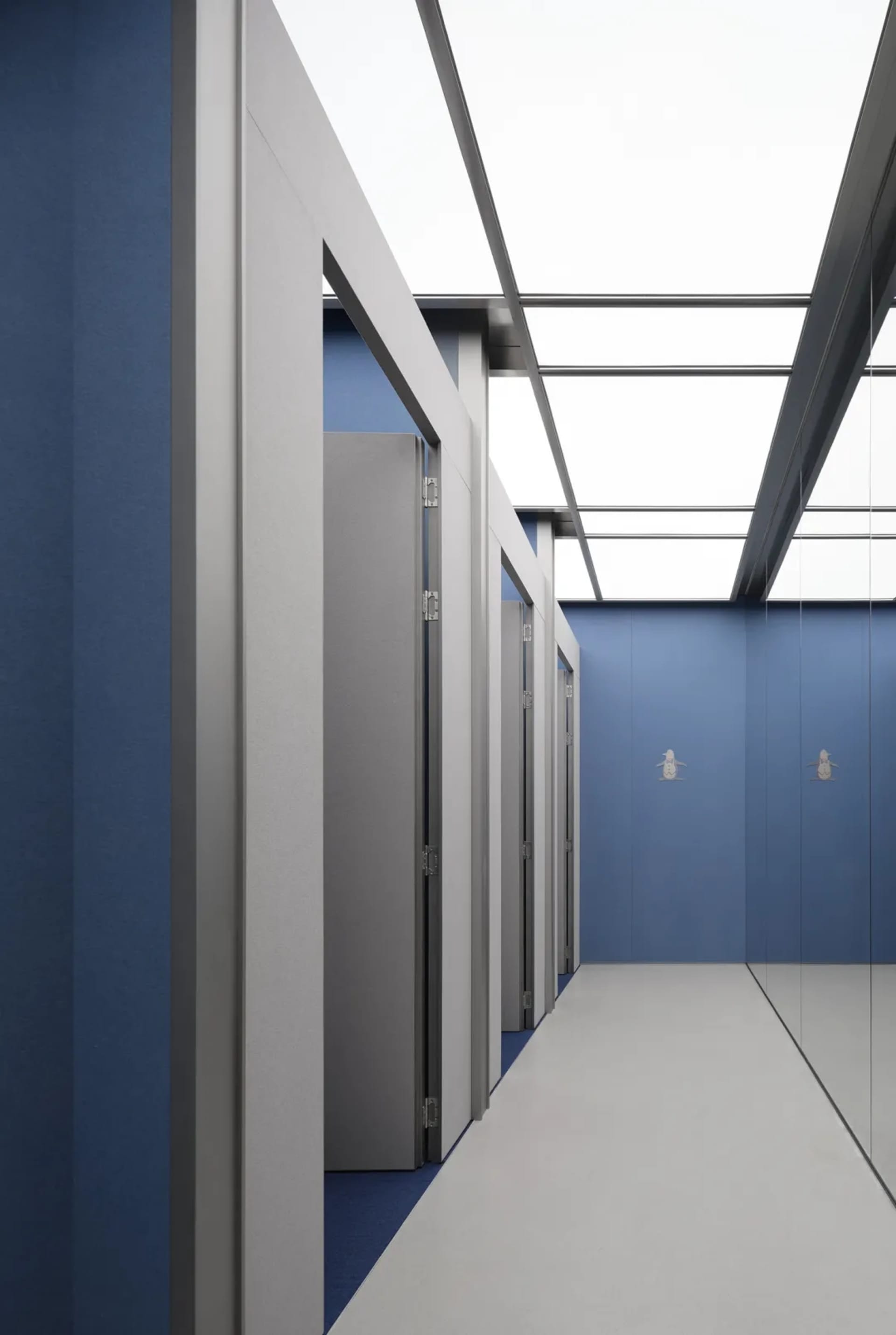 Empty blue hallway with doors on both sides, giving a calm and quiet atmosphere