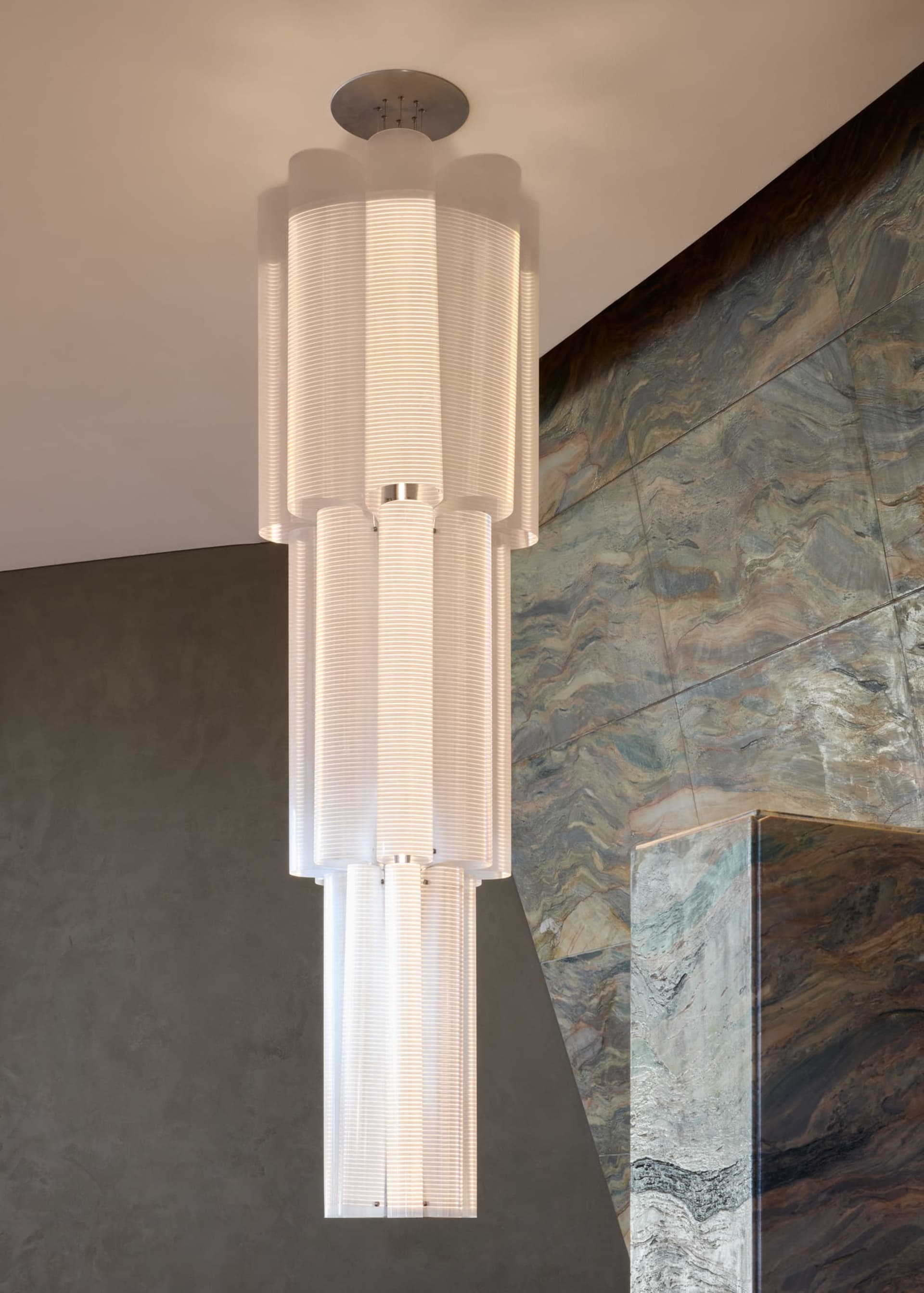 A modern room with stone walls, a large white light fixture, and a warm atmosphere