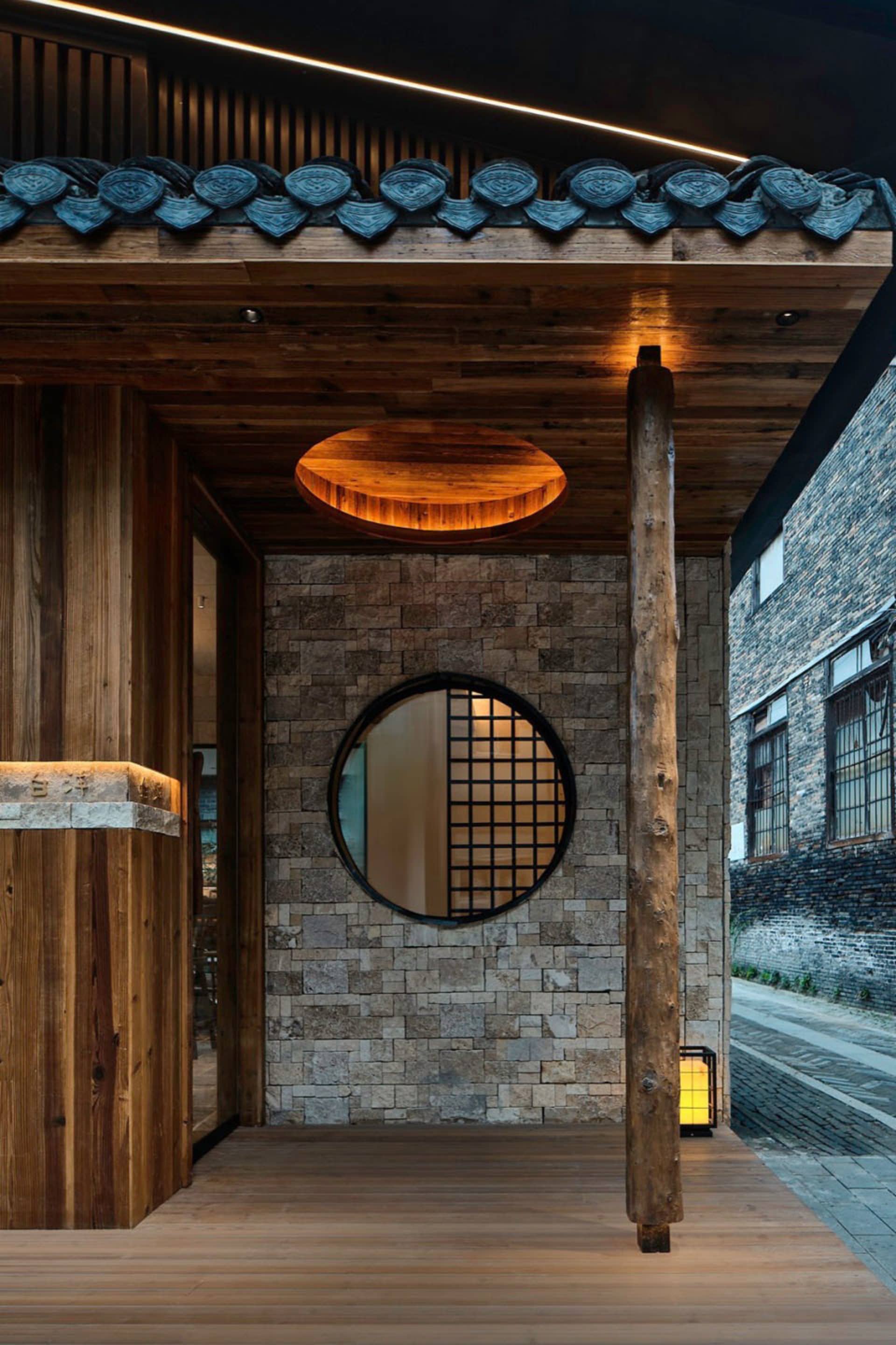 Small Asian-style room with a stone wall, round window, and two side lights, creating a calm and serene atmosphere