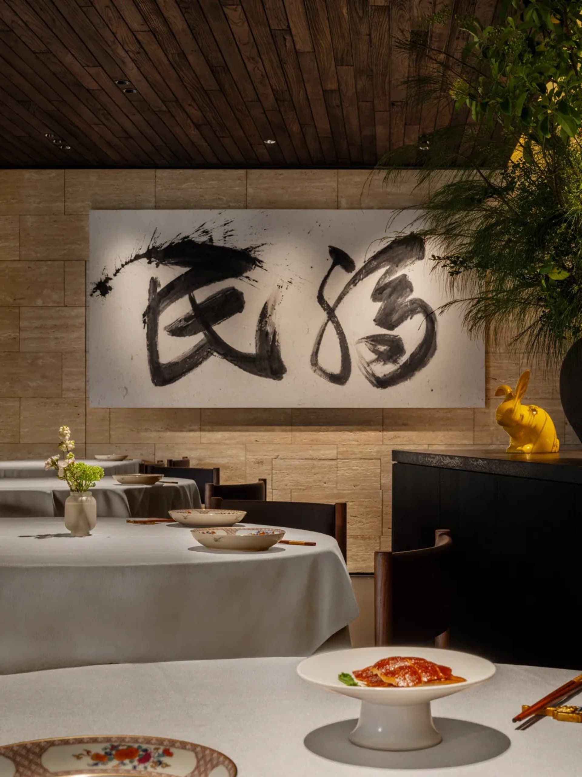 Cozy Asian restaurant interior with dining tables, chairs, artwork on the walls, and vases on the tables