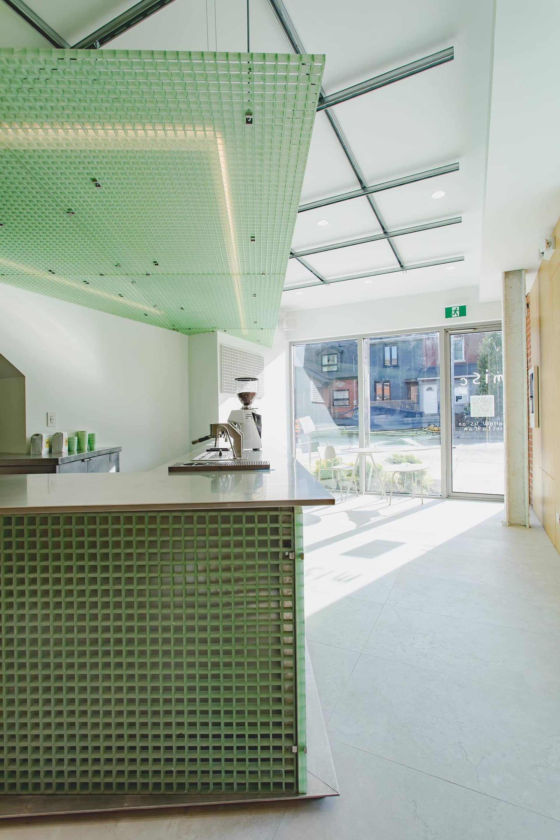 Open kitchen space with green walls, a wooden countertop, and a dining table in the background, featuring a sink and two chairs
