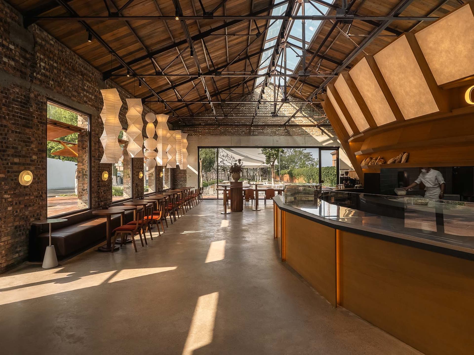 Warm and inviting open concept restaurant with wooden floors, high ceilings, and dining tables and chairs