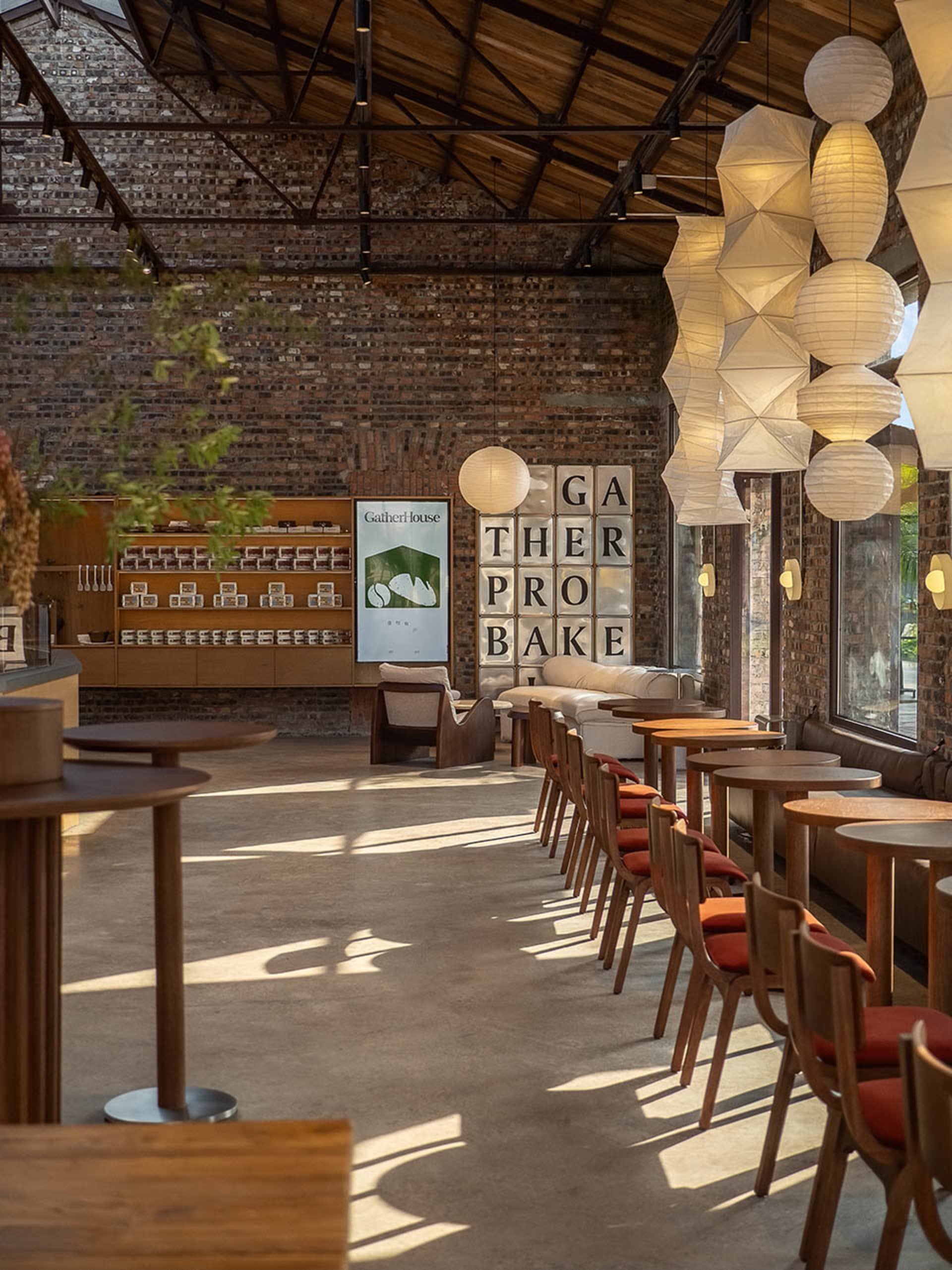 Cozy restaurant interior with a brick wall, wooden tables, and chairs, featuring multiple dining tables and a warm atmosphere