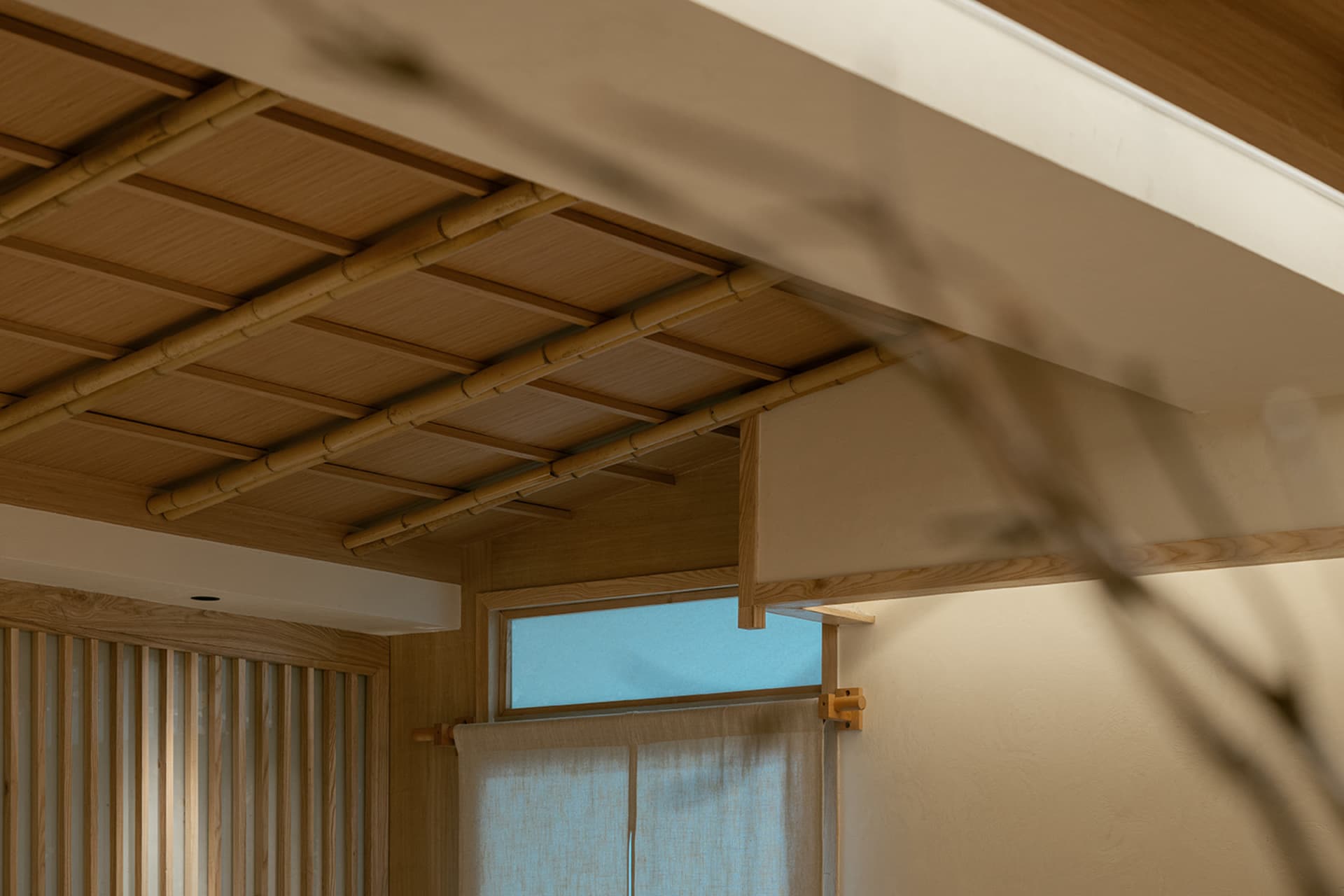 Dimly lit Asian-style living area with wooden walls and ceiling, featuring two windows and a cozy atmosphere