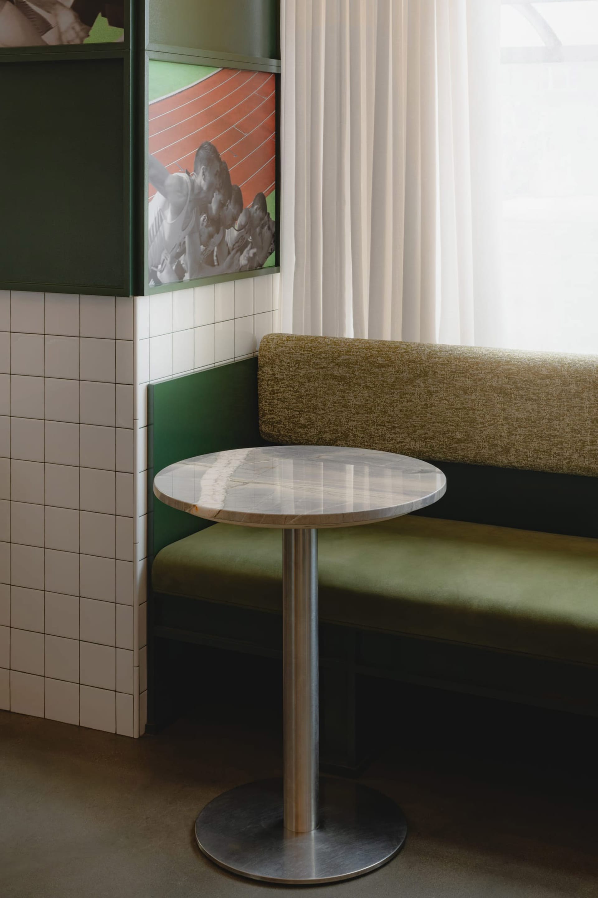 A cozy living space with a green metal bench, a dining table, and a vase, set against a neutral background