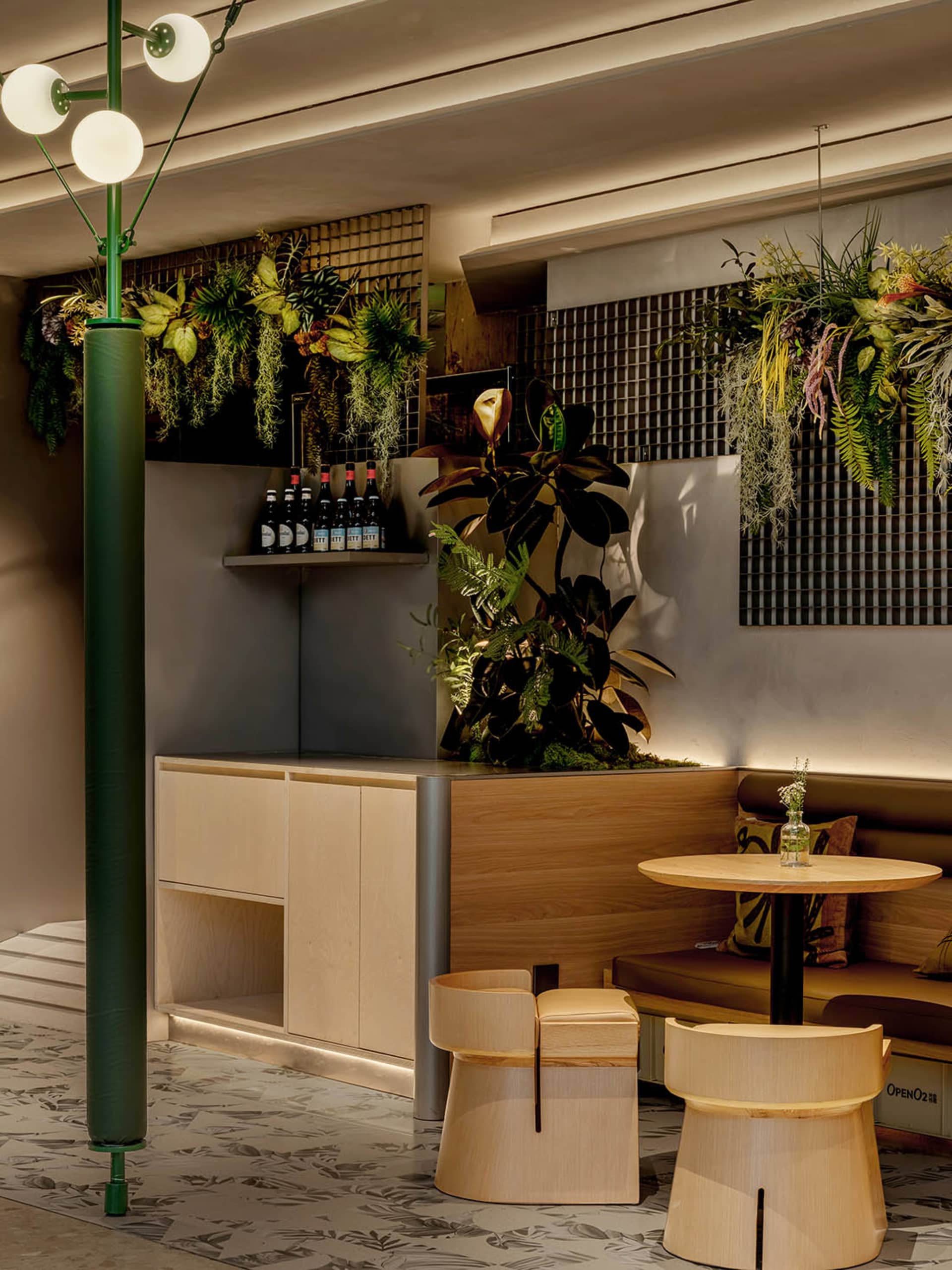 A warm and inviting cafe with a dining table, wooden elements, and multiple potted plants, creating a cozy seating area with a lively atmosphere