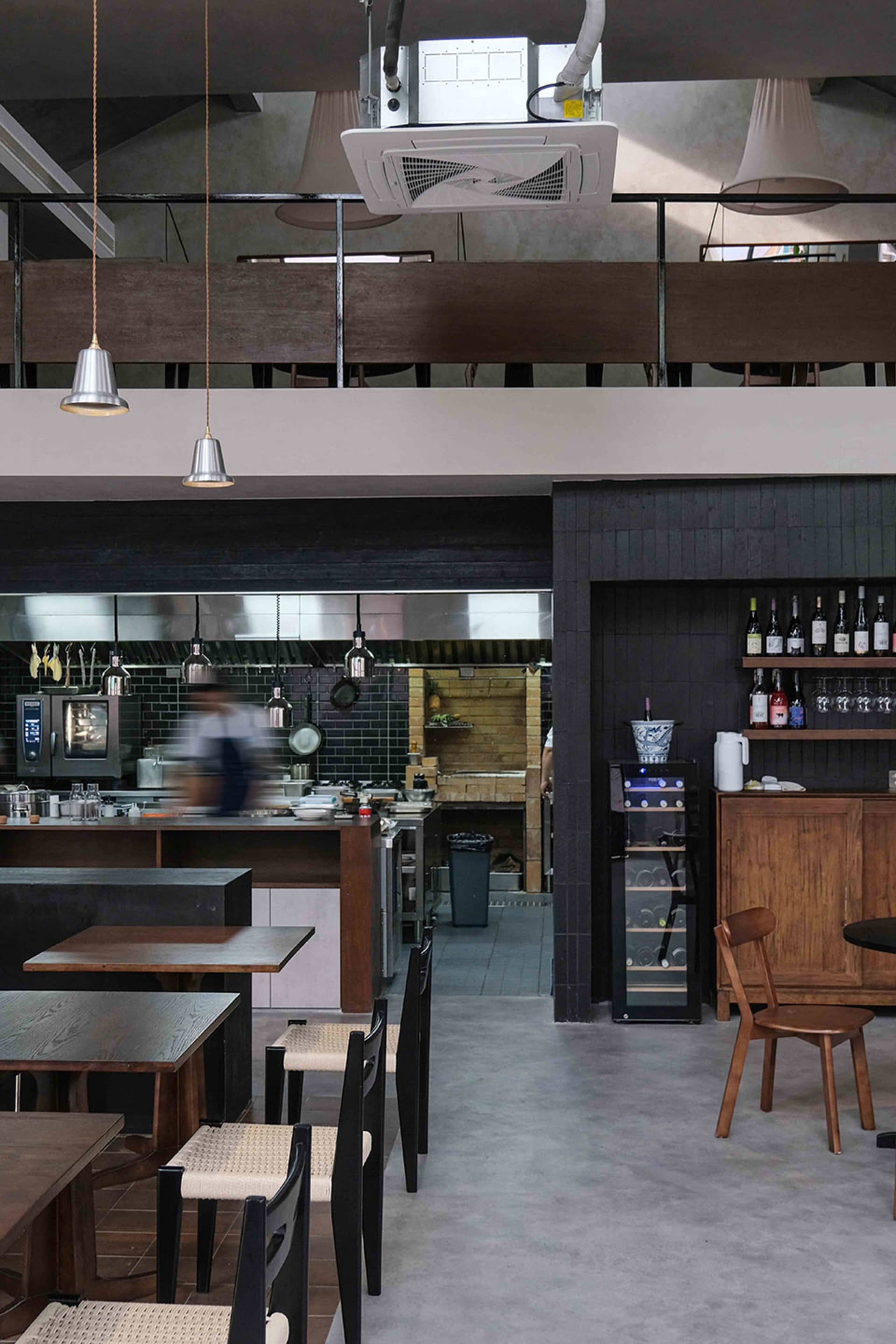 Modern restaurant interior with black walls, white elements, tables, chairs, kitchen appliances, and bottles of beverages