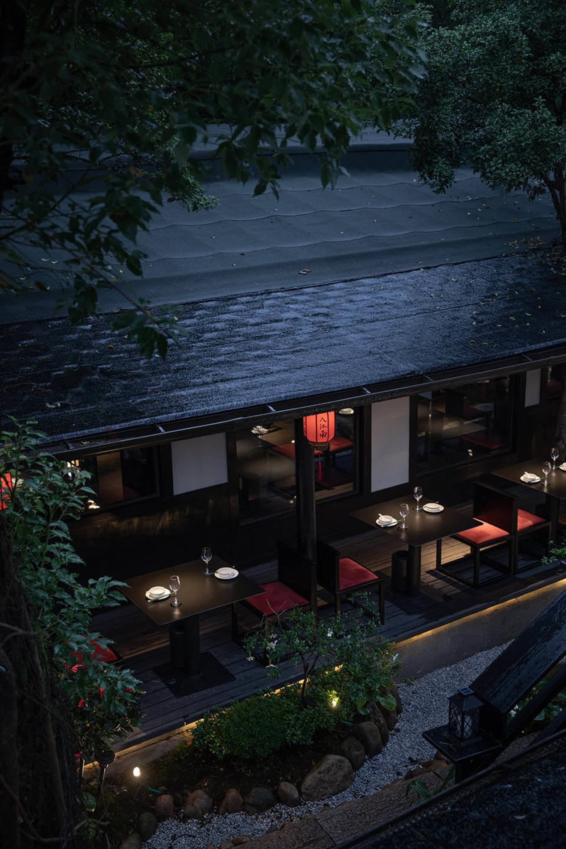 優雅亞洲餐廳，具黑色屋頂、木質地板，以及餐廳空間內整齊排列的餐桌椅，有些桌上擺放著酒杯