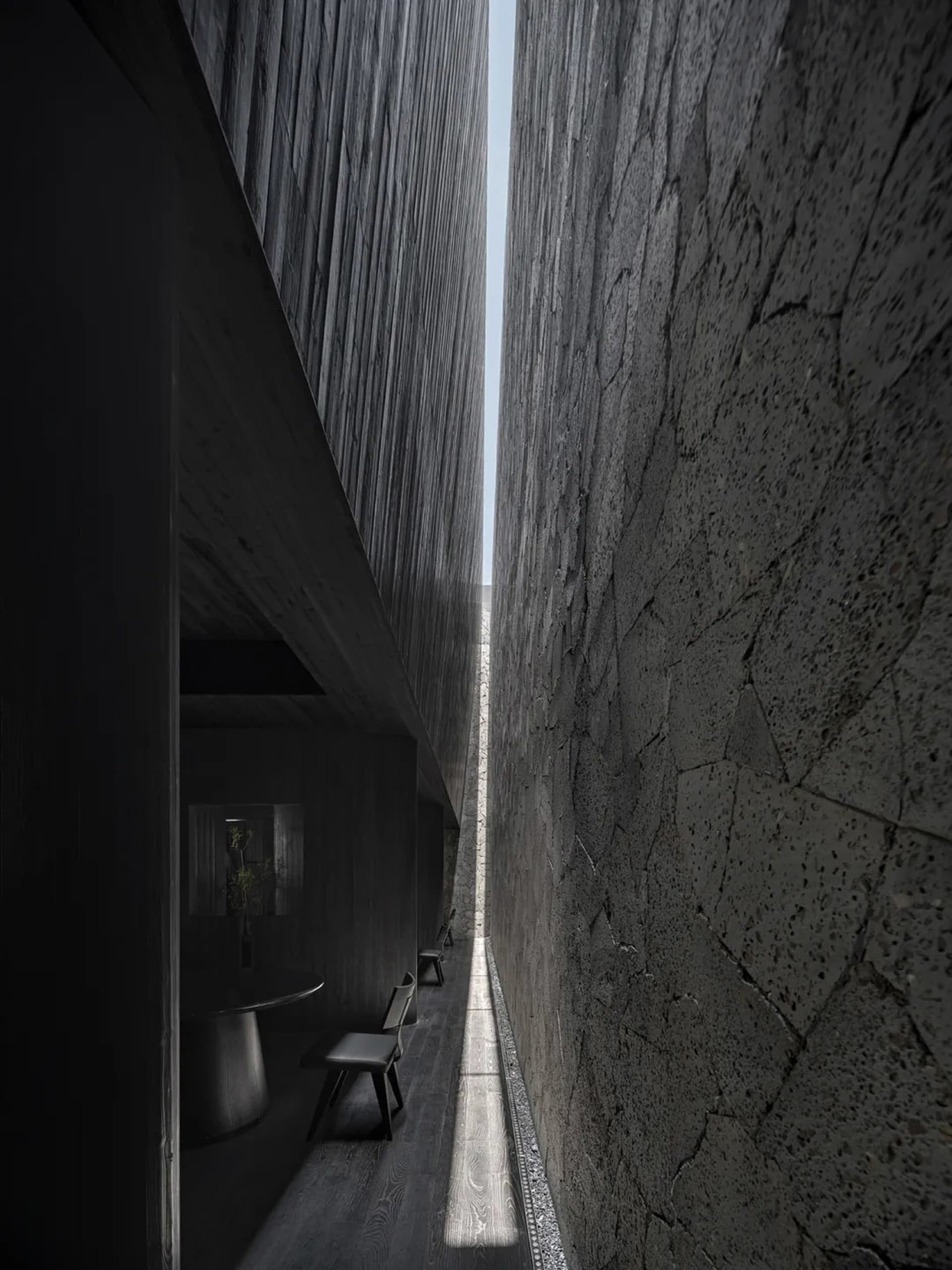 A narrow hallway with three black chairs placed along the walls, suggesting a residential or office space