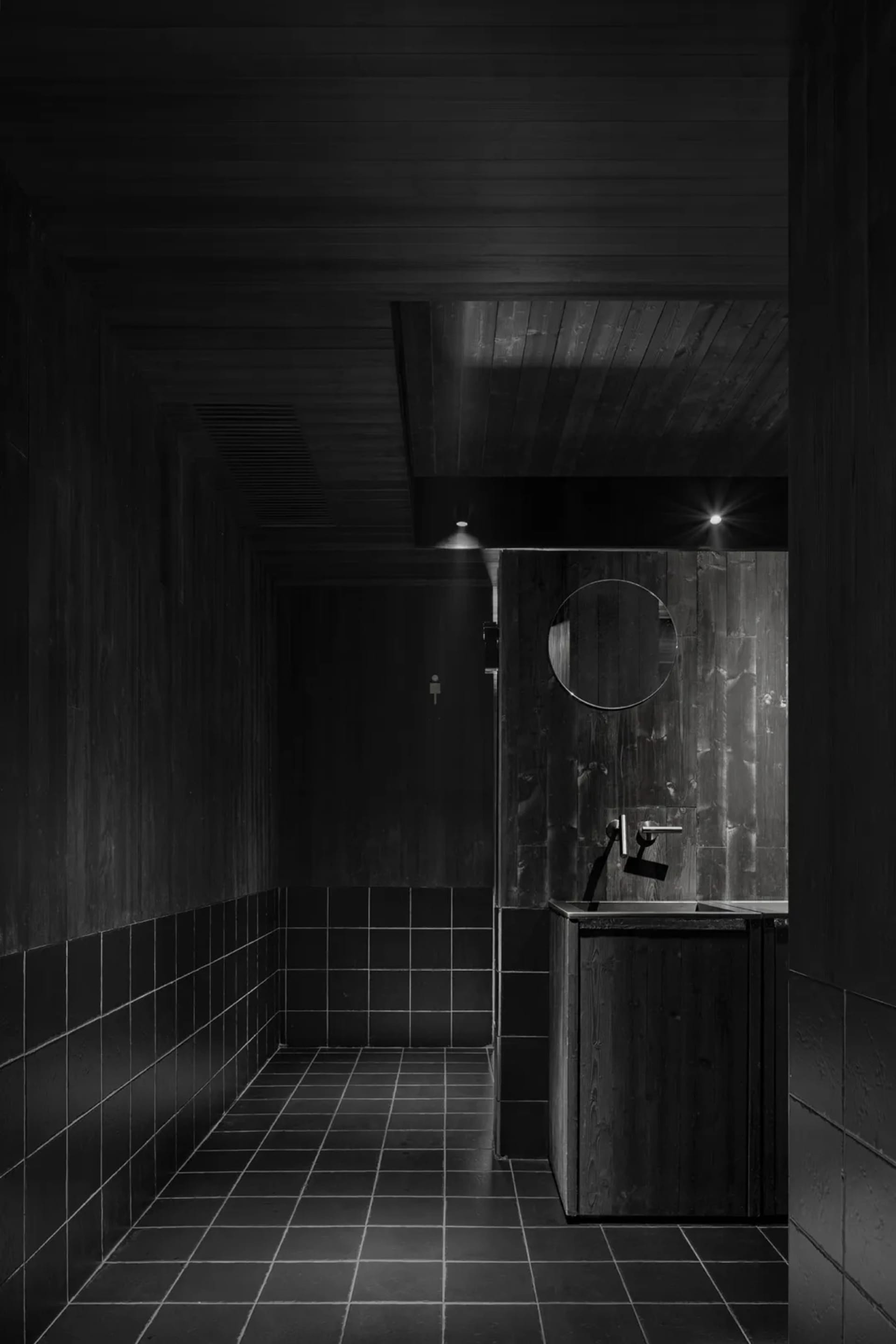 A minimalist bathroom with two sinks, a shower stall, and a mirror above the sink area, set against a neutral background