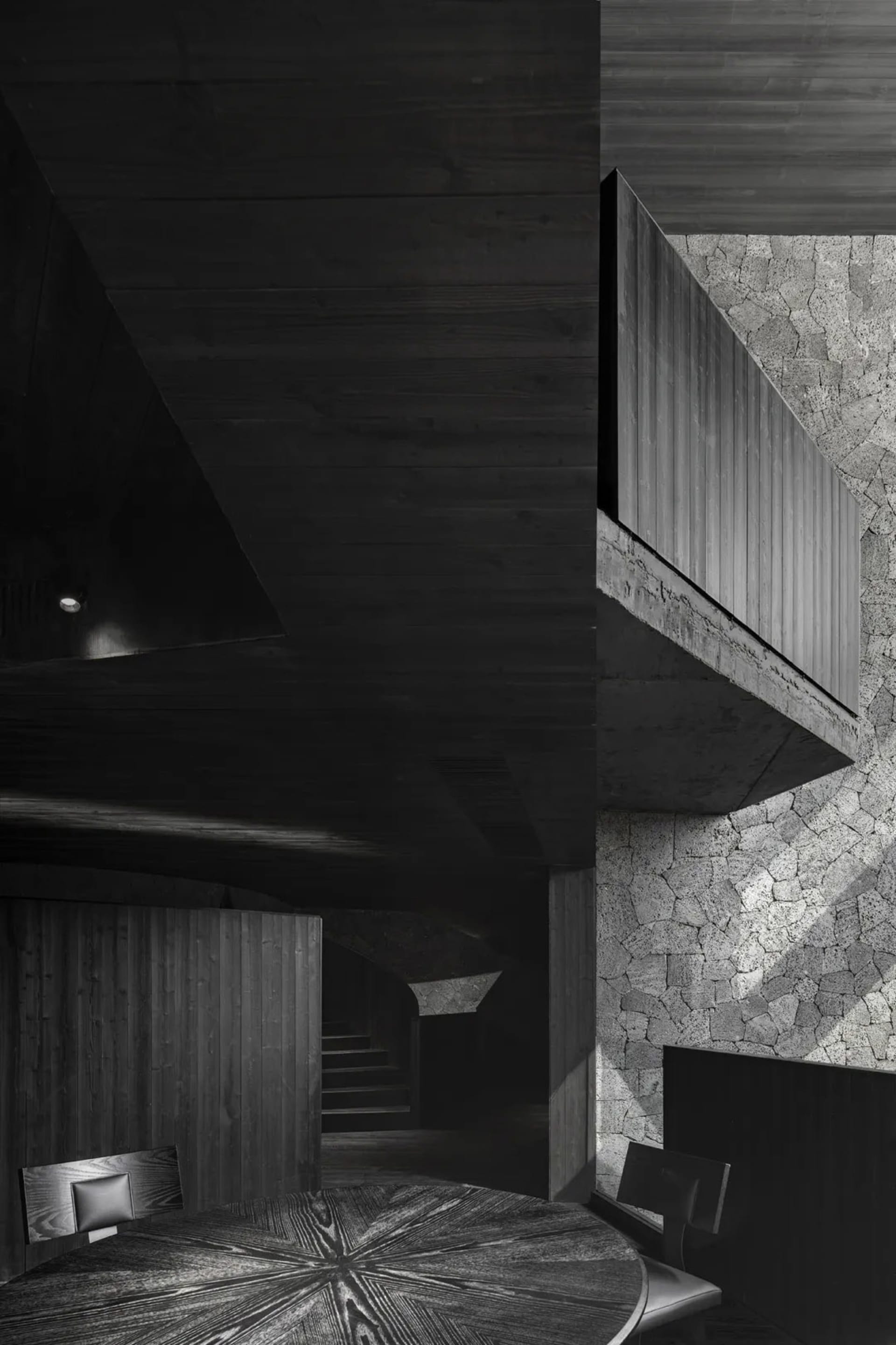 Black and white photo of a building with a concrete staircase leading to a lower level, creating a sense of depth and intrigue
