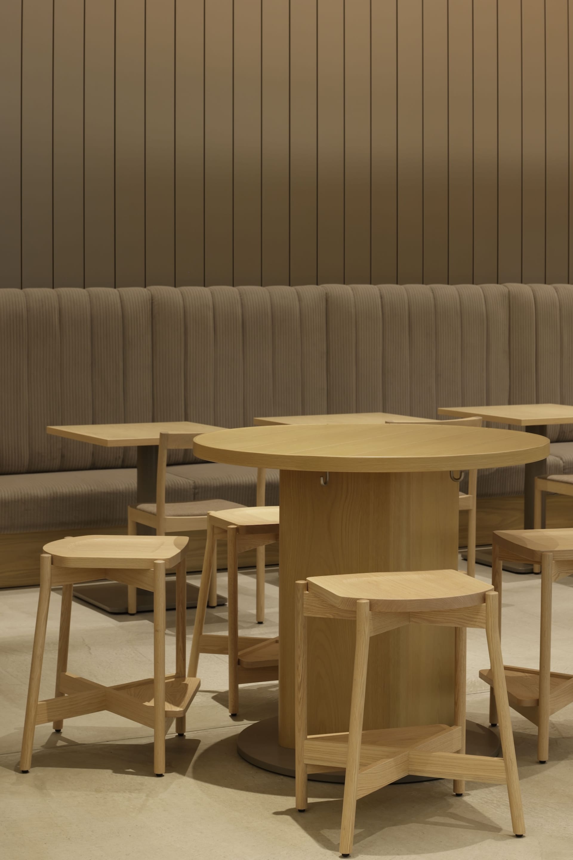 Warm and inviting restaurant interior with wooden tables and chairs, multiple benches, and a central dining table
