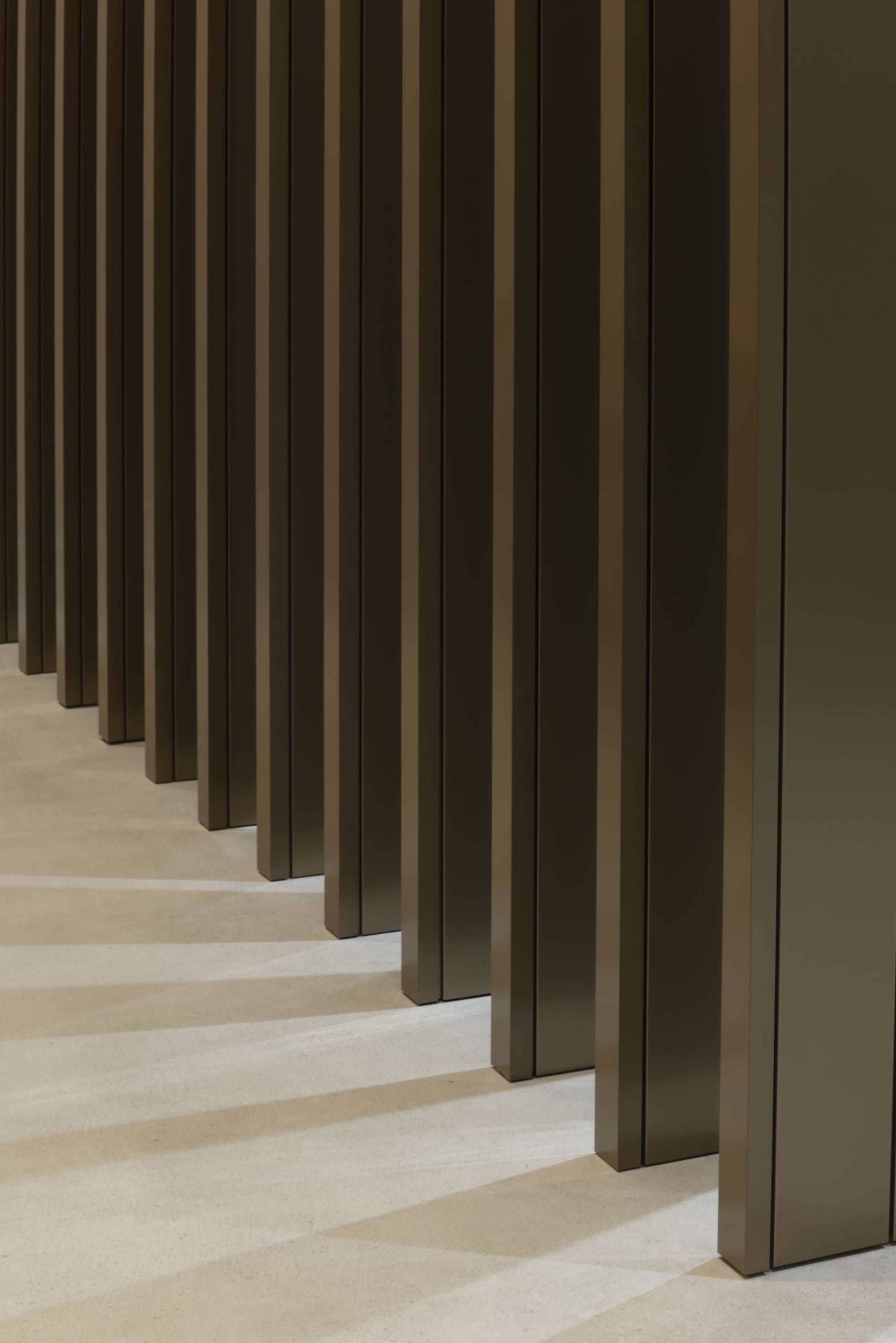 A dimly lit empty hallway with tall wooden pillars on either side, giving an eerie atmosphere