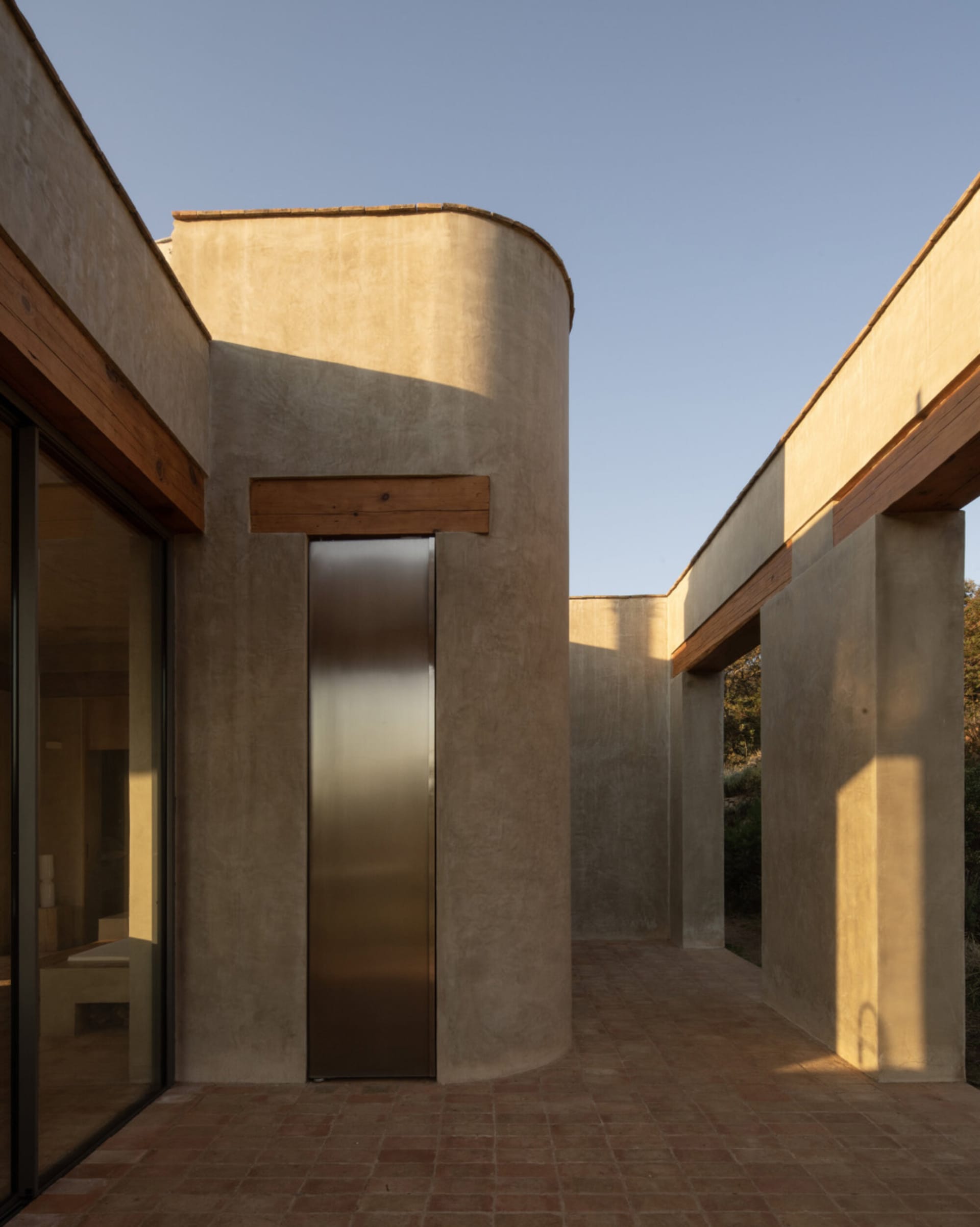 Modern building with a large glass door, metal staircase, concrete walls, and two windows on each side, providing ample natural light