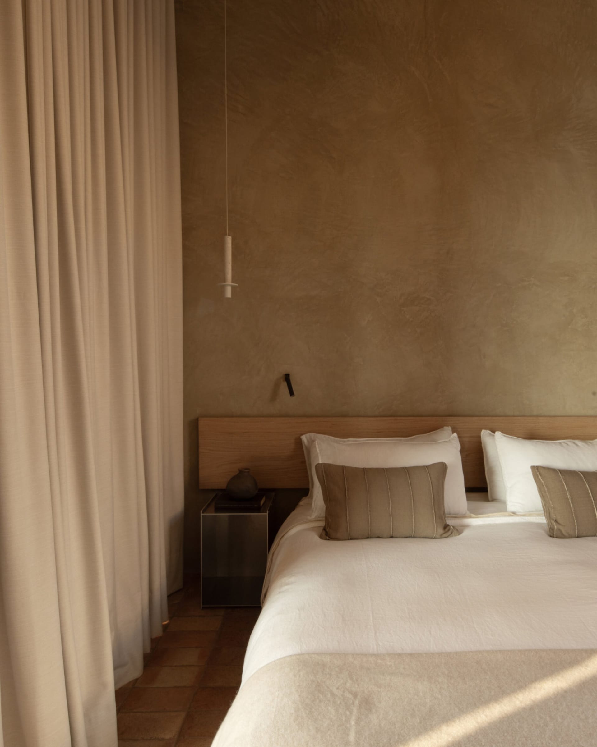 Twin bedroom with two beds, wooden floor, pillows, blankets, and lamps, creating a warm and inviting atmosphere