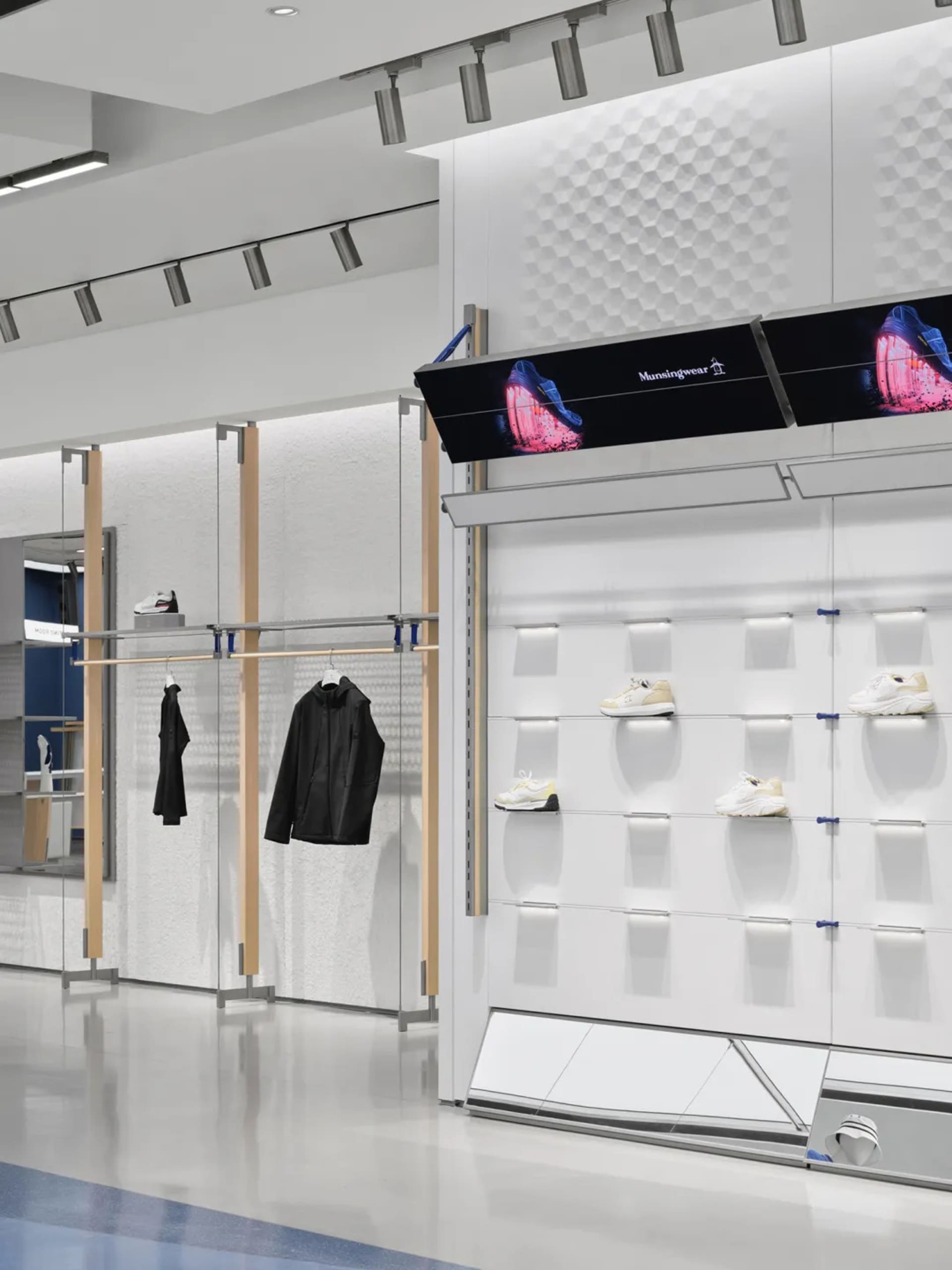 A modern retail space with white walls and multiple rows of shelves displaying various shoes in a well-organized manner