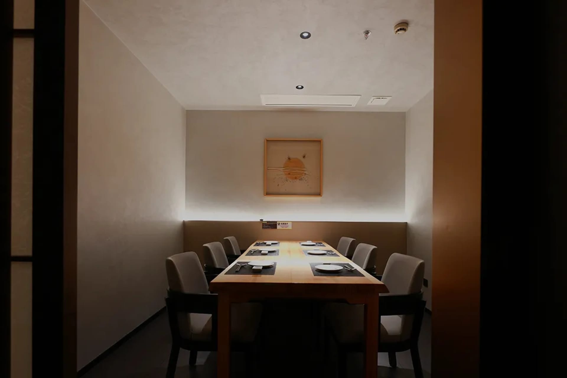 A well-lit and inviting restaurant dining area with a long wooden table surrounded by multiple chairs, creating a calm atmosphere for guests to enjoy their meals
