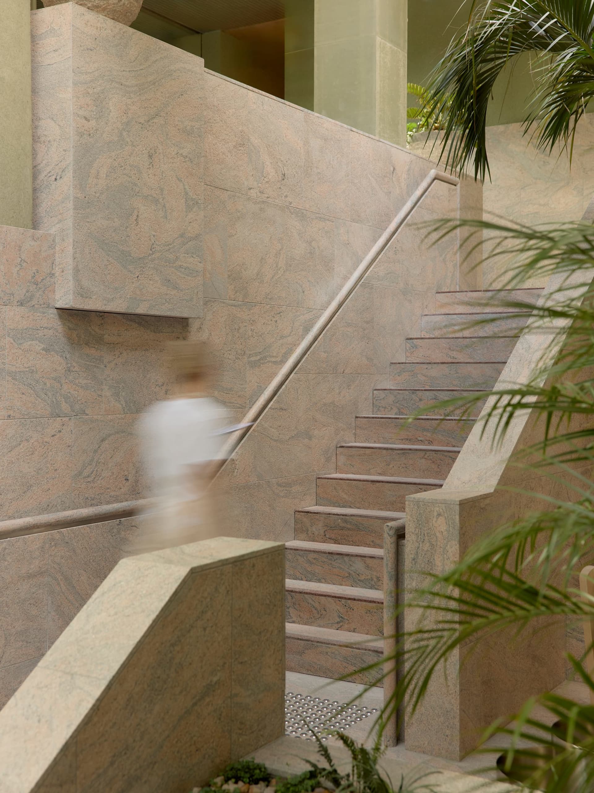 A modern hotel staircase with marble steps, surrounded by natural light and a sophisticated atmosphere