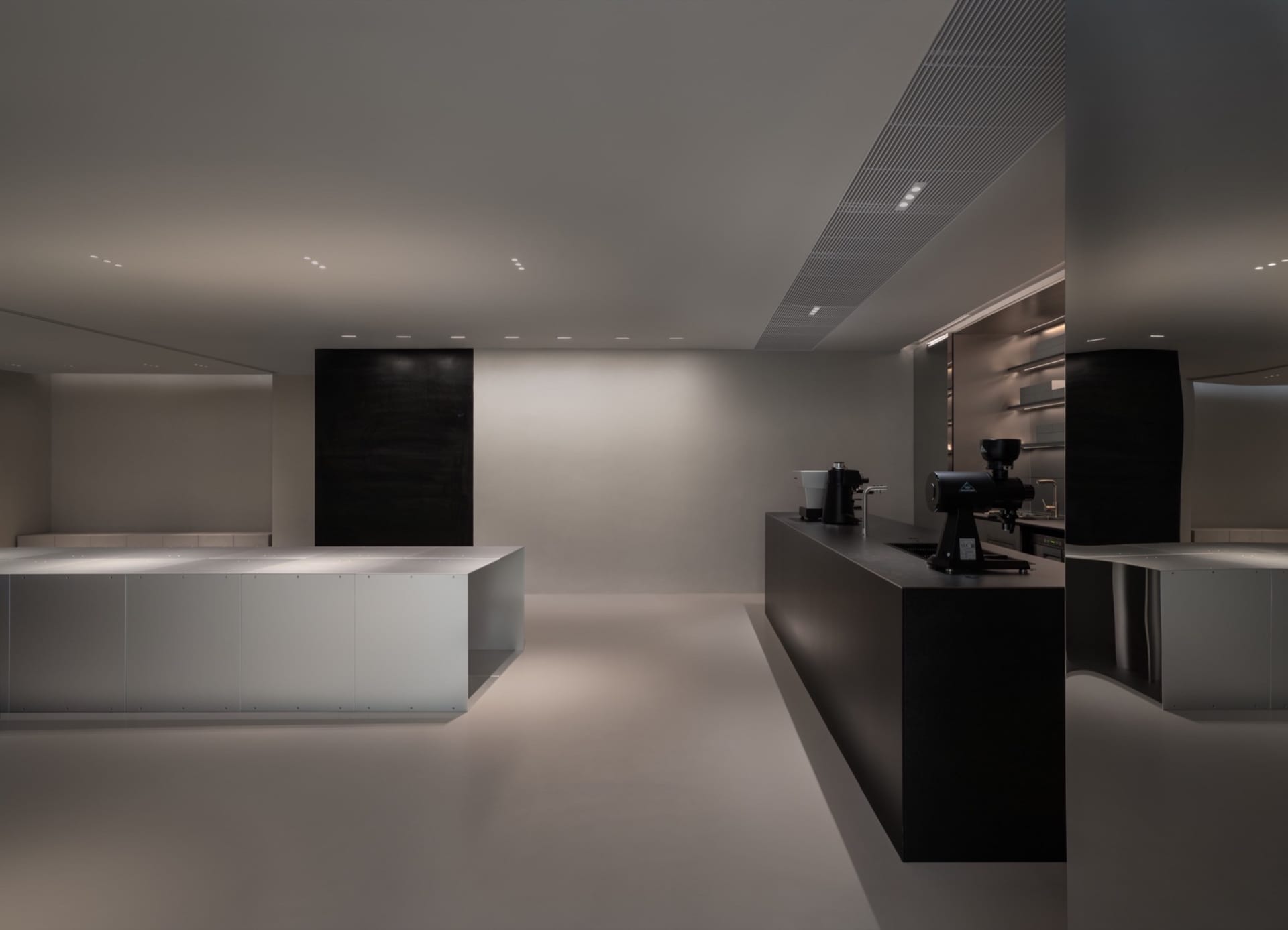 Commercial kitchen with white walls and floors, featuring modern appliances and minimalistic design