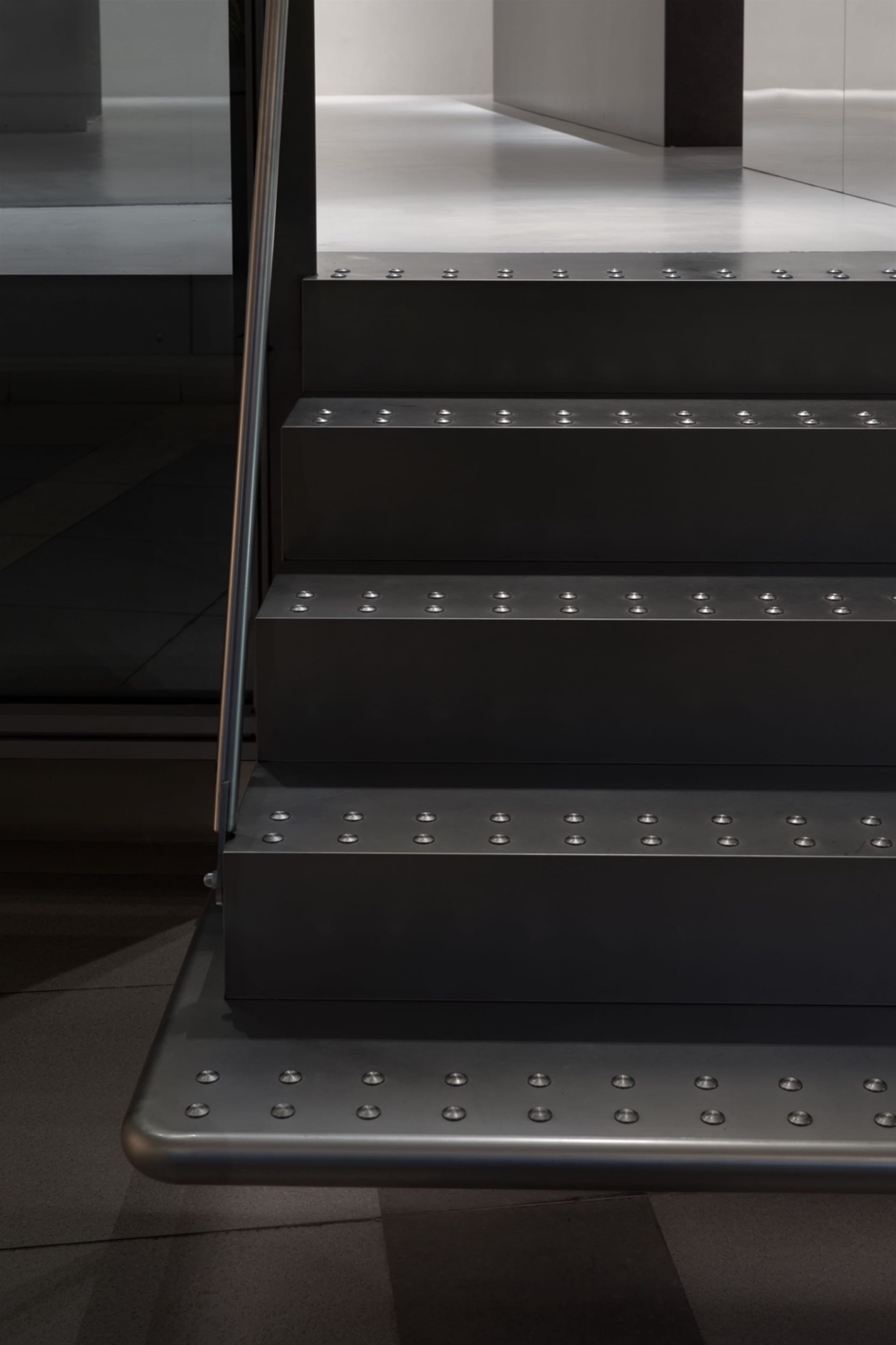 A modern metal staircase with a sleek and contemporary design, set against a dark background