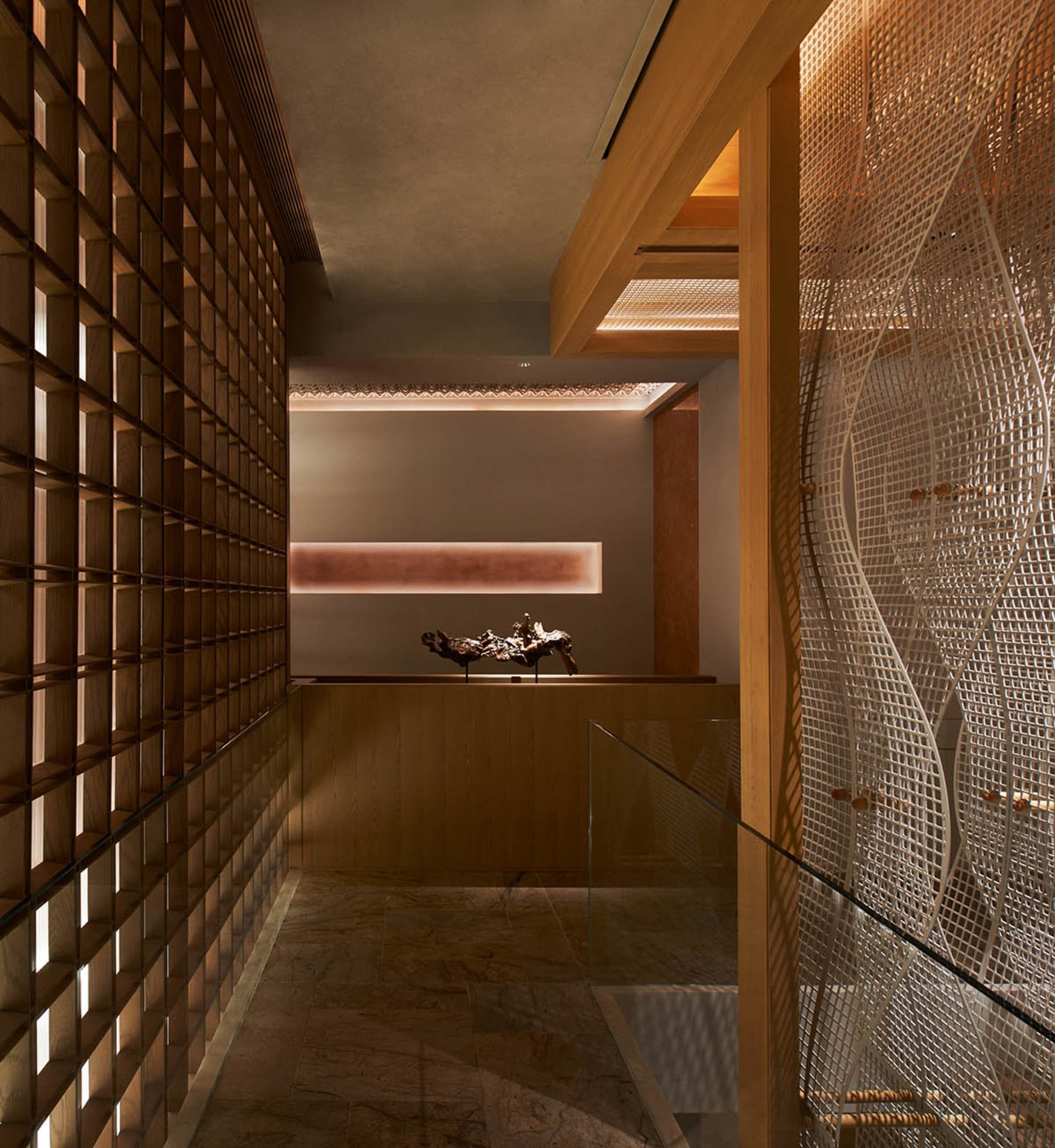 A modern hallway with a glass partition separating two rooms, featuring a wooden floor and natural light from windows on both sides