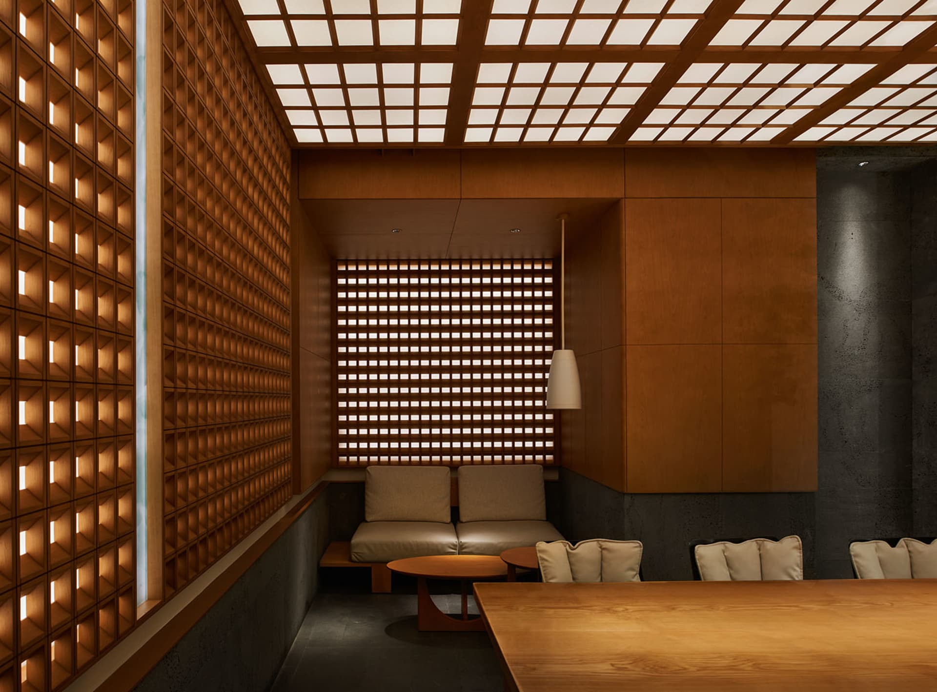 Cozy restaurant interior with wooden walls, metal accents, and a dining table surrounded by chairs in a dimly lit space