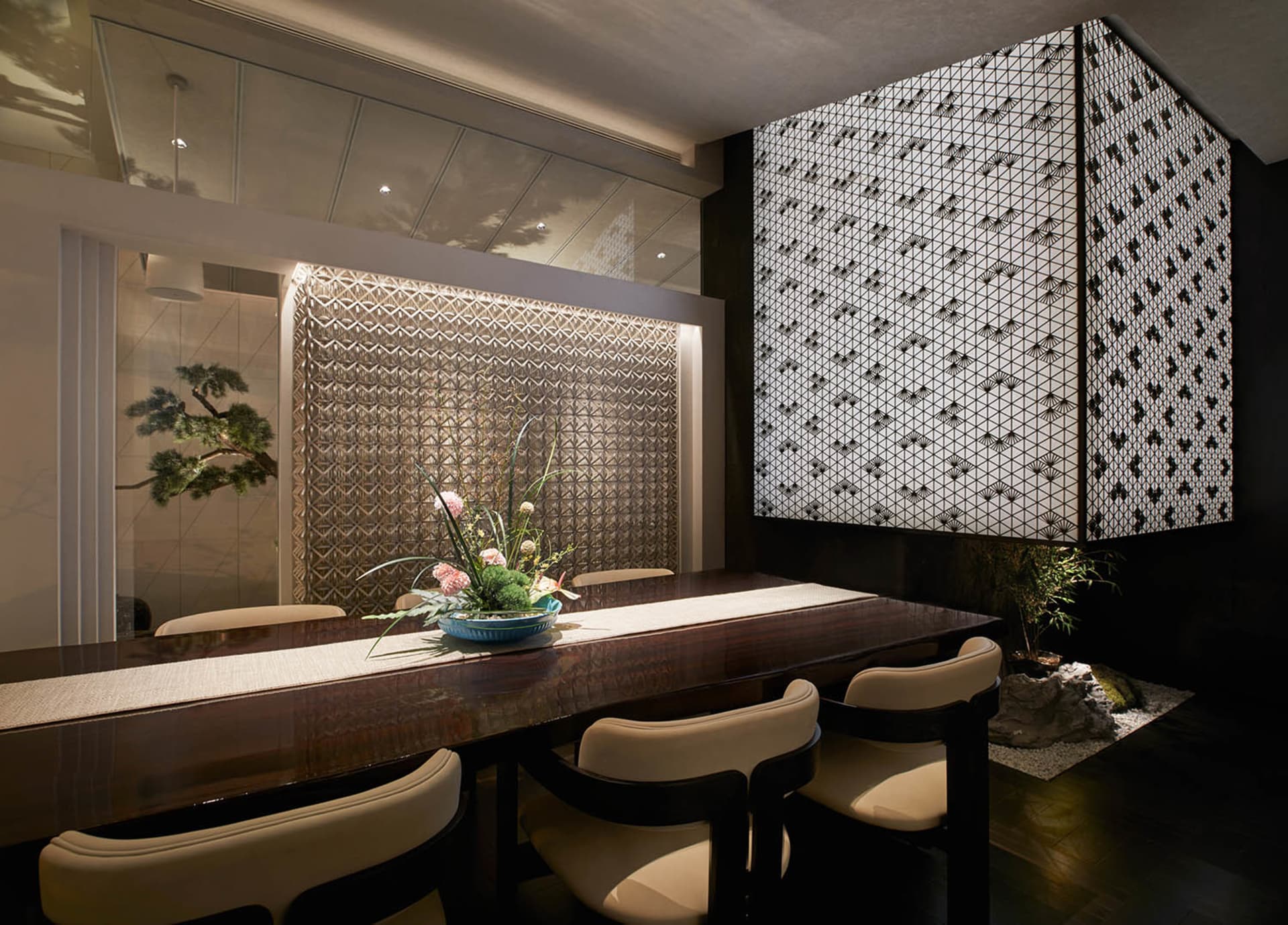 Dining area with a patterned wall, a table, chairs, and potted plants, creating an elegant and inviting atmosphere
