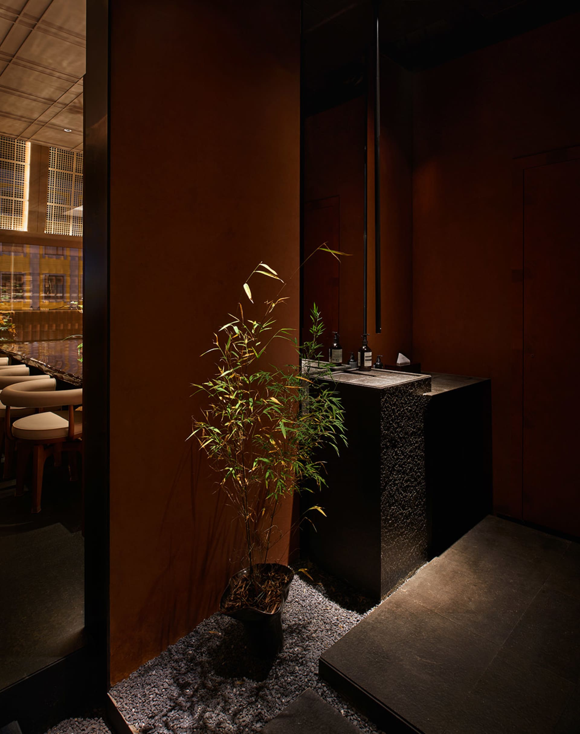 Modern restaurant interior with a black countertop, chairs, a potted plant, and a bottle, conveying a stylish atmosphere