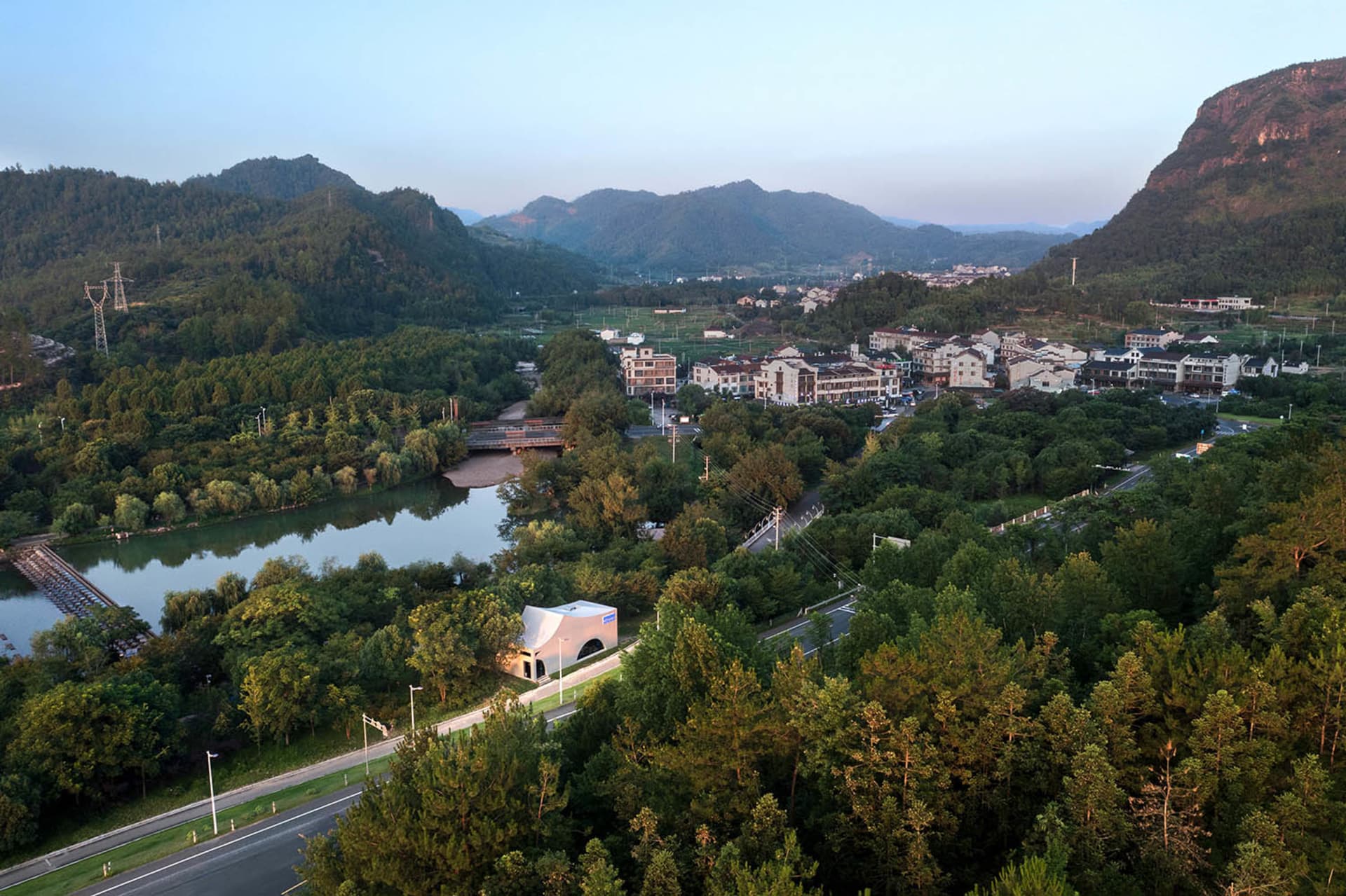一座寧靜的小鎮坐落於山谷中，四周環繞著山巒，各種建築與樹木增添了環境的自然美感