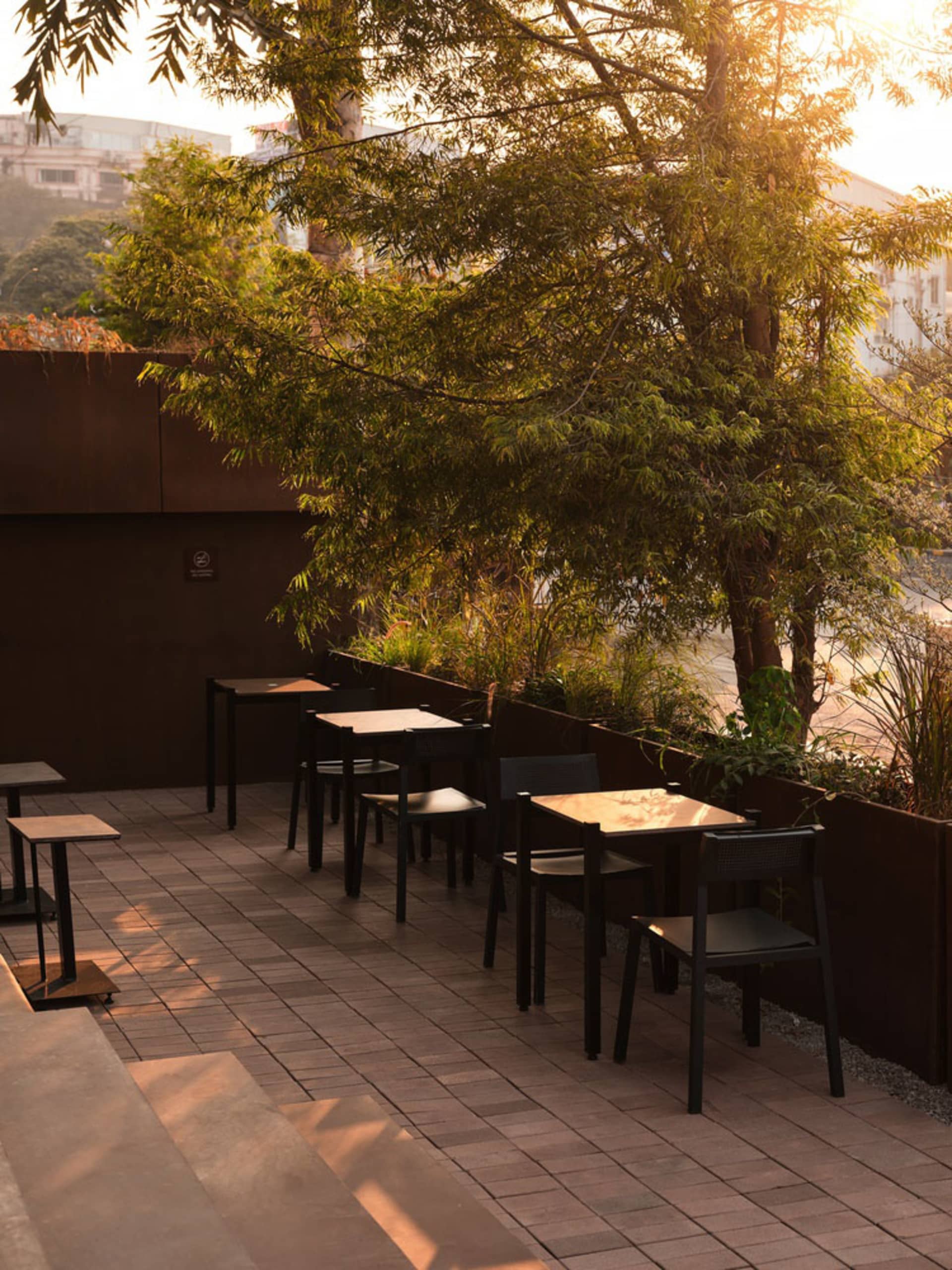 A restaurant patio with black tables and chairs, surrounded by an inviting atmosphere