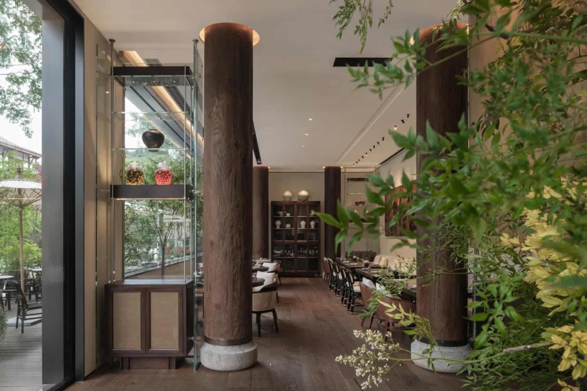 Warm and inviting restaurant interior with wooden columns, dining tables, and chairs, featuring vases and a focus on wood as the primary material