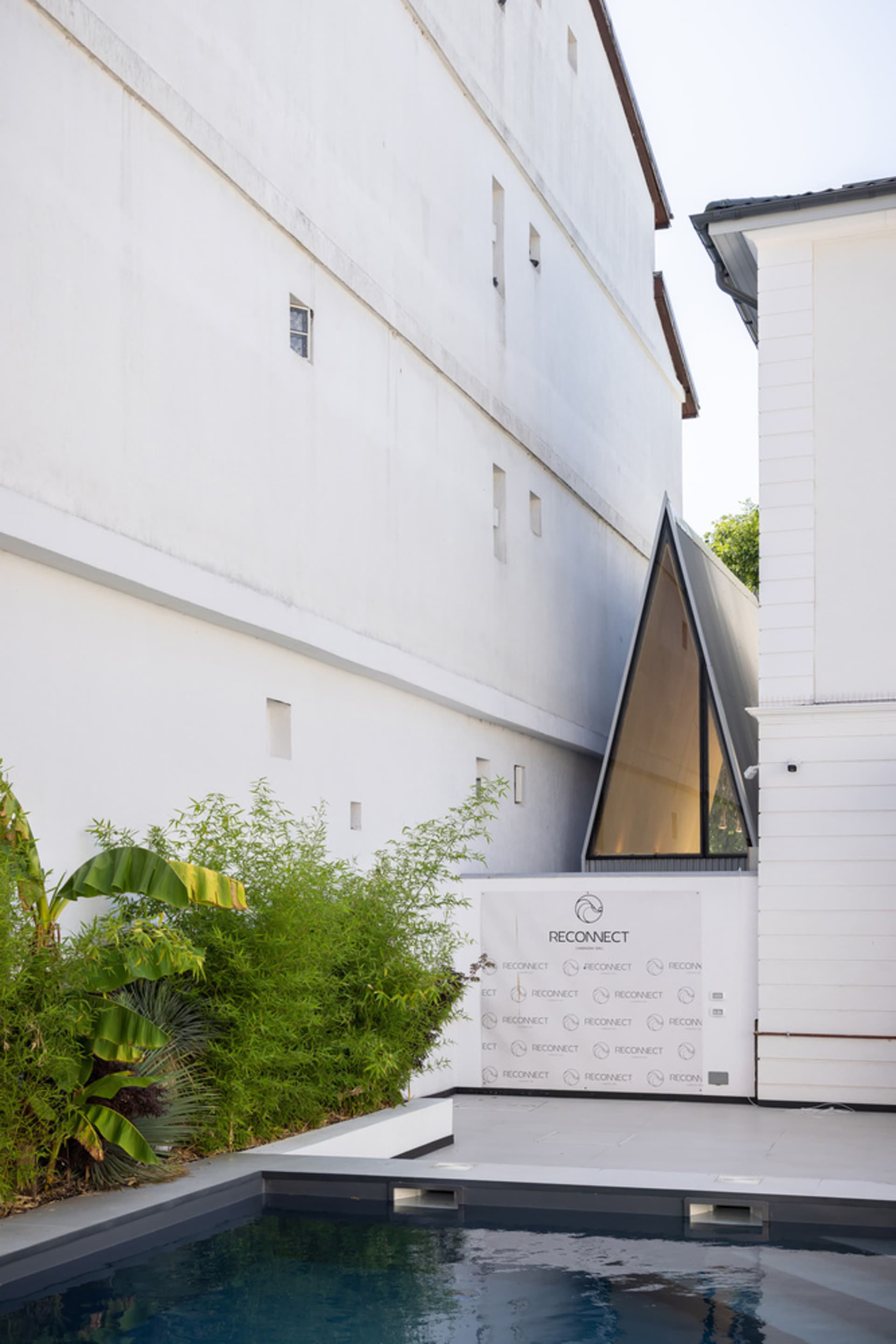 A modern building with a large white wall featuring two windows, one large and one small, made of concrete with a sturdy and solid appearance