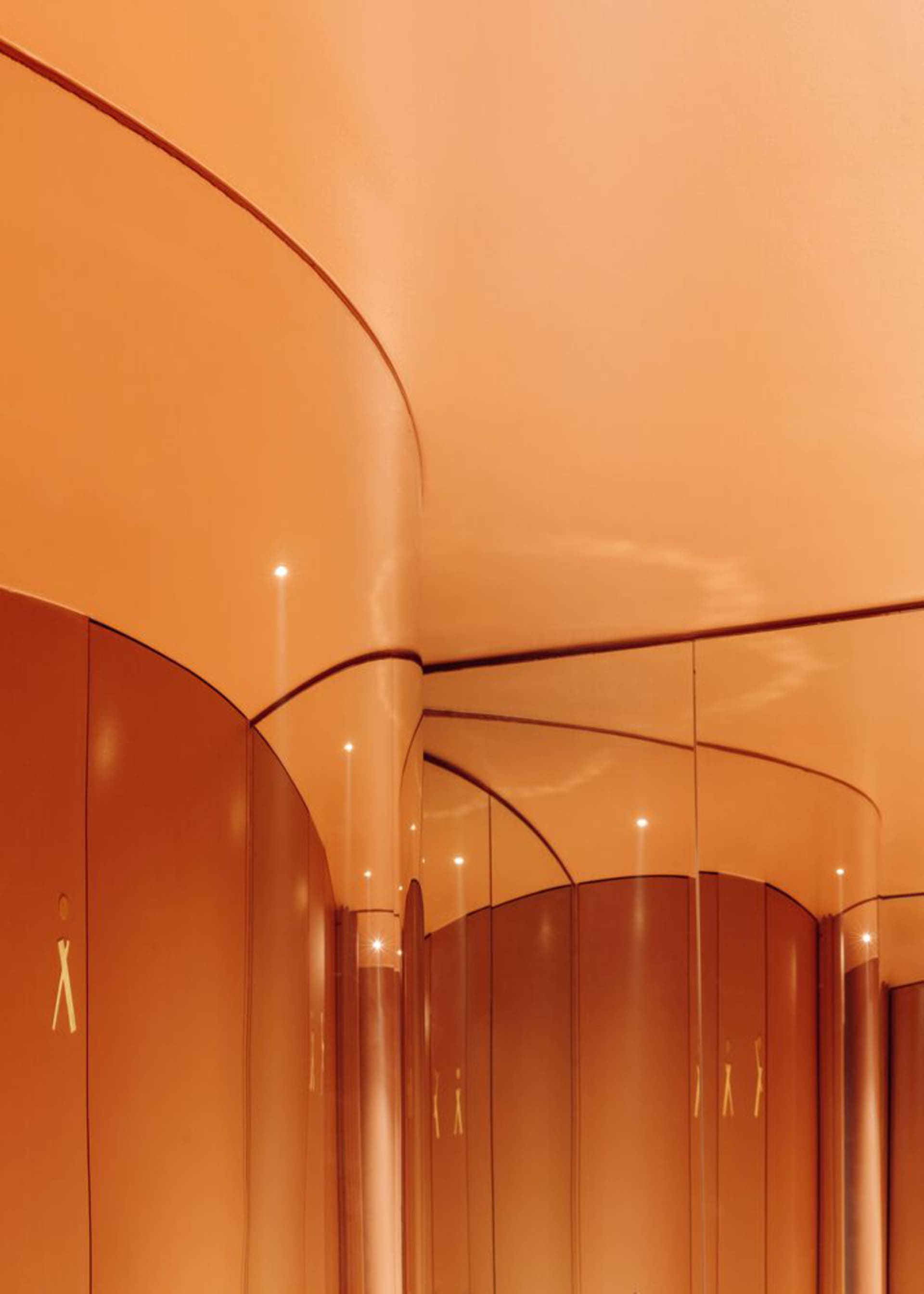 Warm and inviting orange hallway with curved walls, gold accents, and overhead lighting