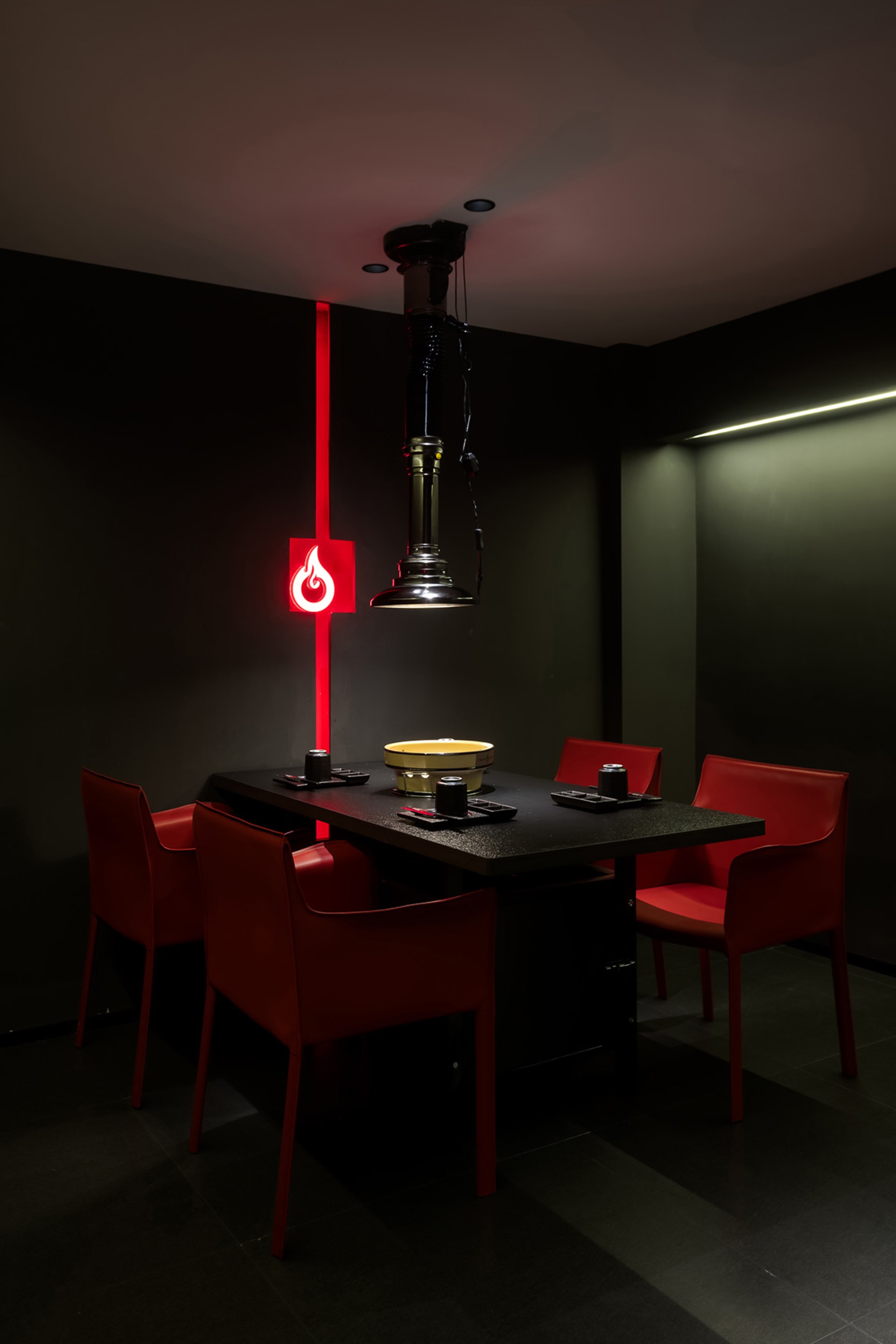 Dining space with a black table and red chairs, set for a meal with a bowl on the table, in a modern and stylish atmosphere