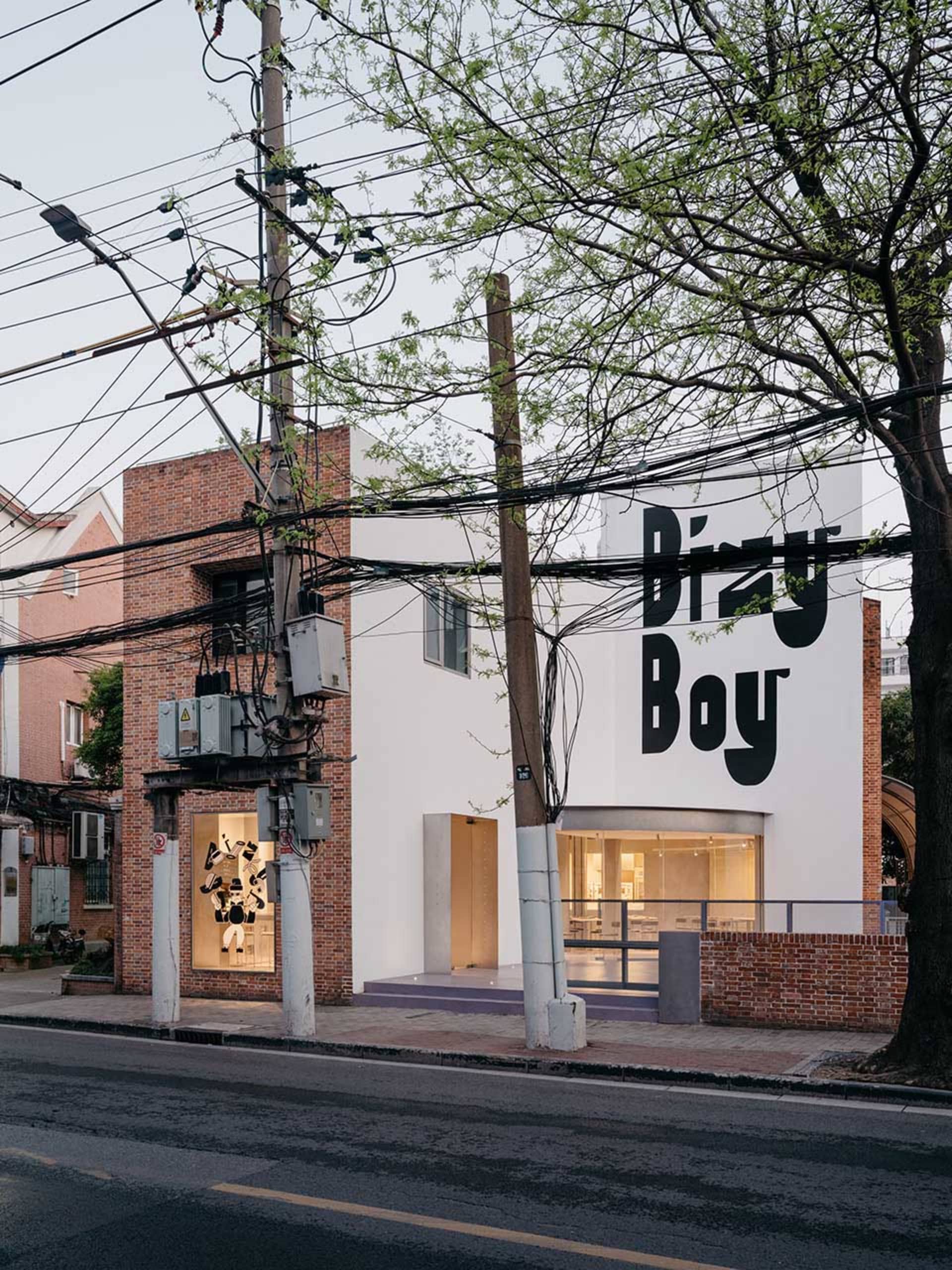 A brick building with a large white wall featuring graffiti, surrounded by people and bicycles