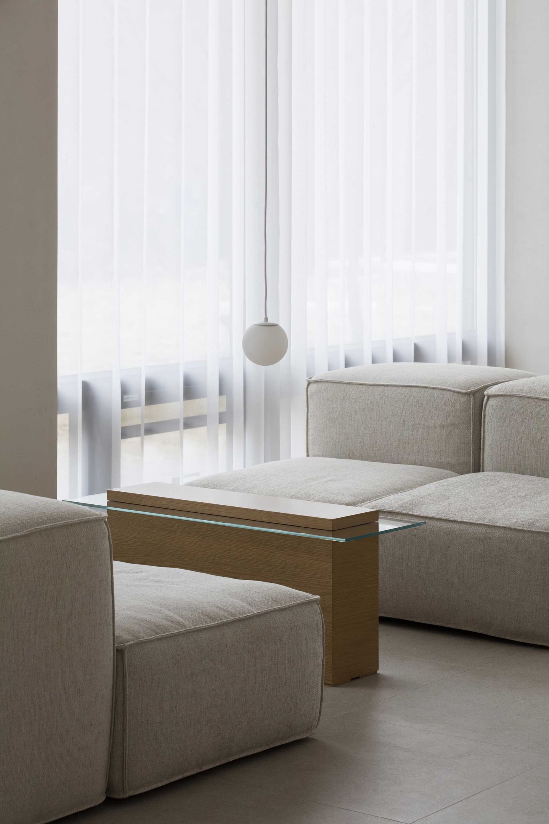Comfortable living space with two couches, chairs, and a dining table, surrounded by white walls and curtains, with wooden furniture and a warm atmosphere