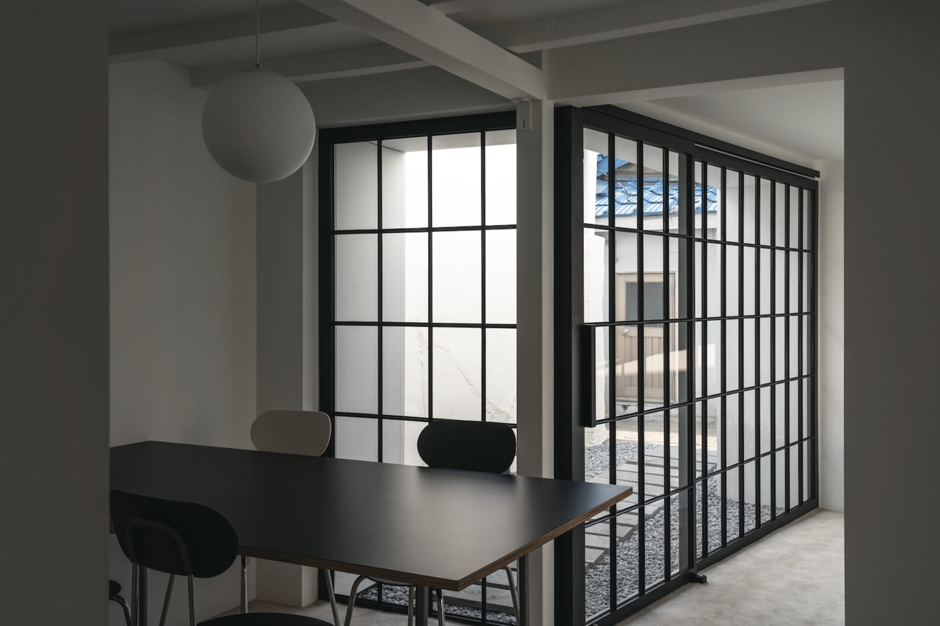 A well-lit dining space with a black table surrounded by chairs and a couch near the left wall